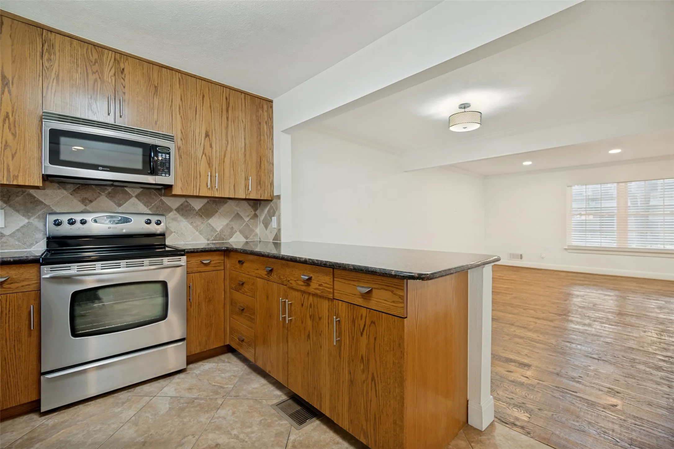 Kitchen featuring wood-finish cabinetry, stainless steel appliances, and a tiled backsplash