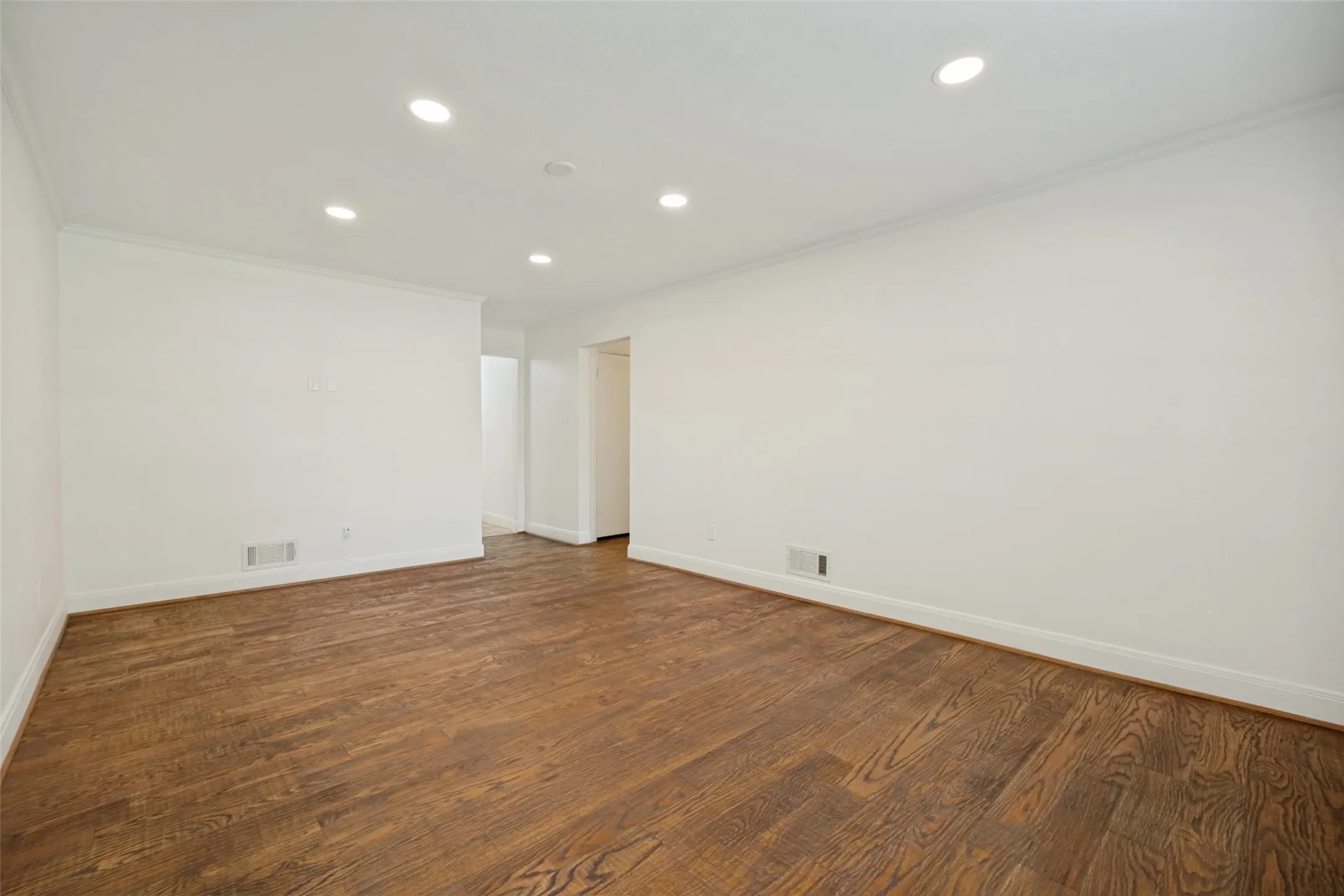Recessed lighting, crown molding, wood-finish flooring, white walls, and white trim