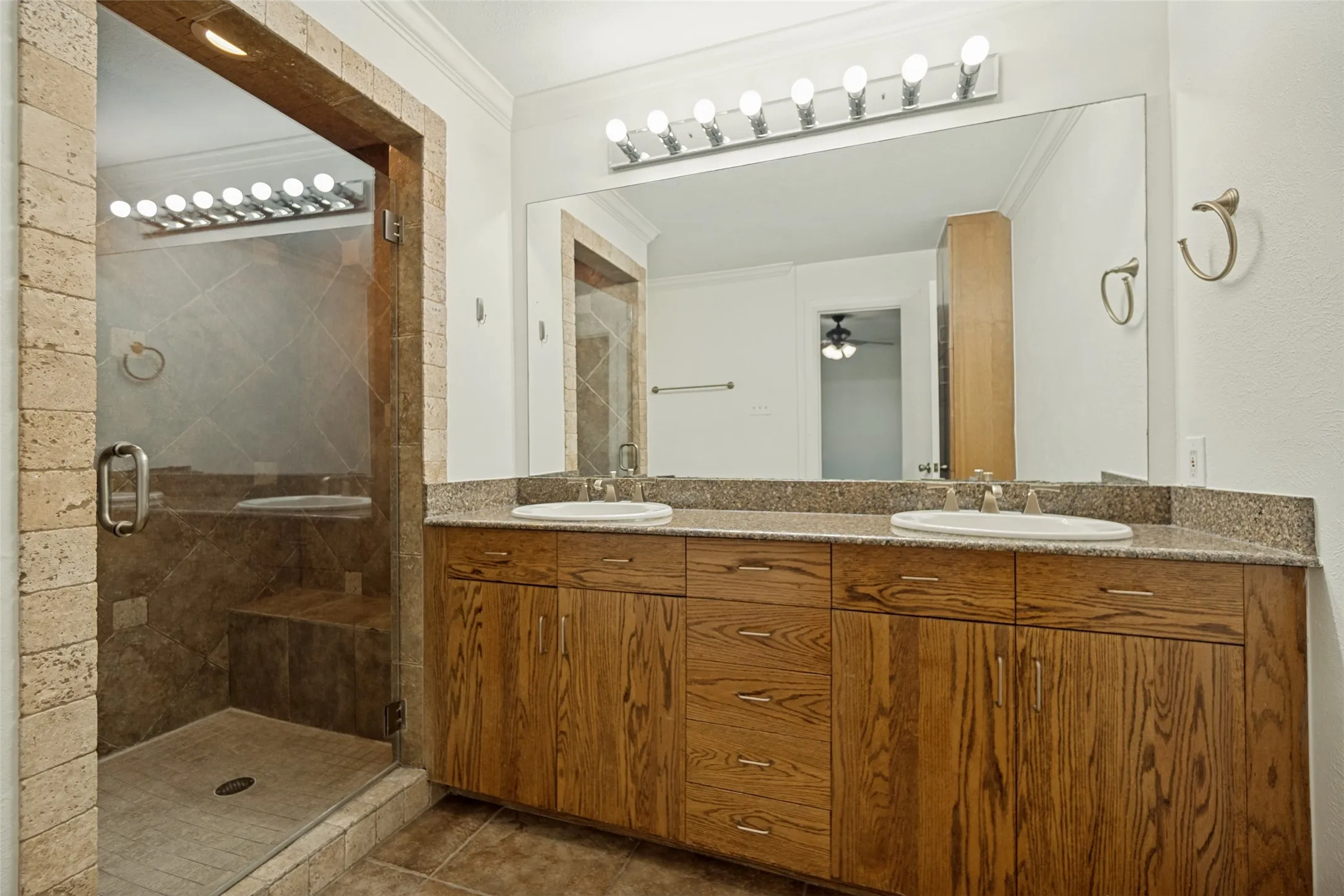 Dual vanity with wood-finish cabinetry and stone-finish countertop