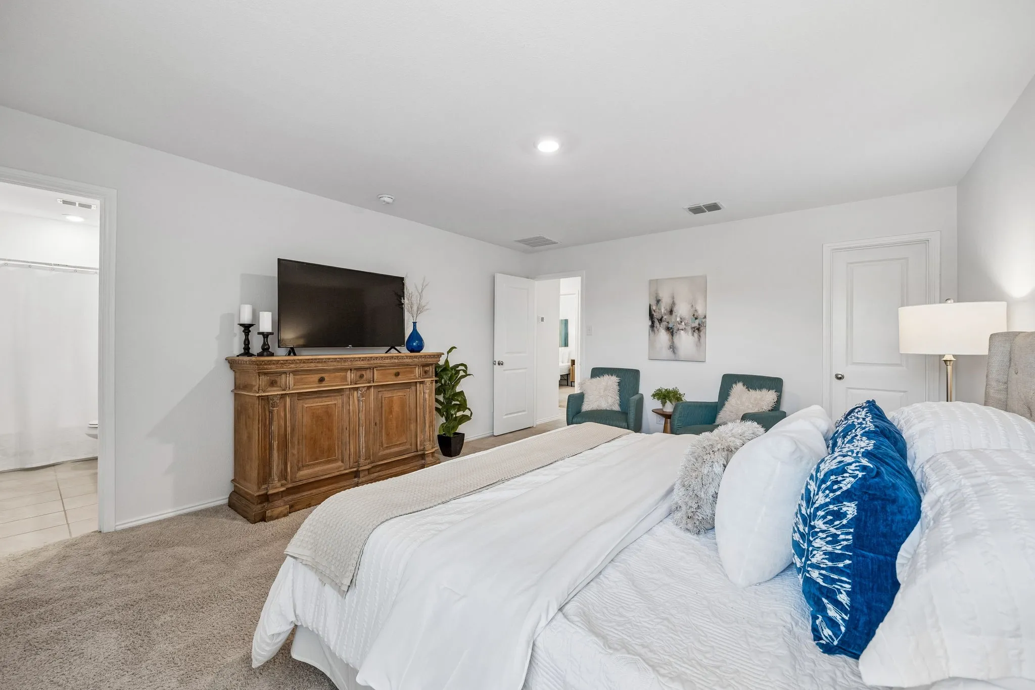Recessed ceiling lighting, neutral-toned carpeting, and a doorway to an adjacent bathroom with tile flooring