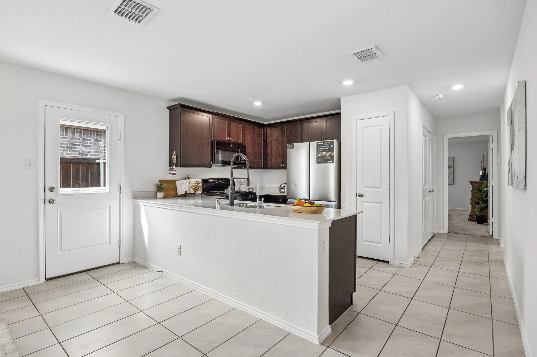 Kitchen with dark wood cabinetry, white stone countertops, and stainless steel appliances