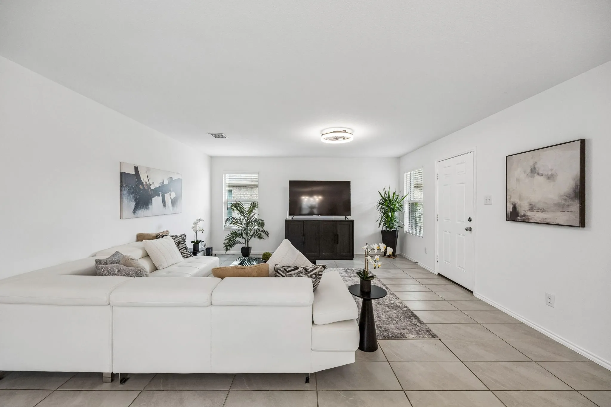 Open-concept living space featuring tiled flooring, white walls, and a contemporary ceiling light fixture
