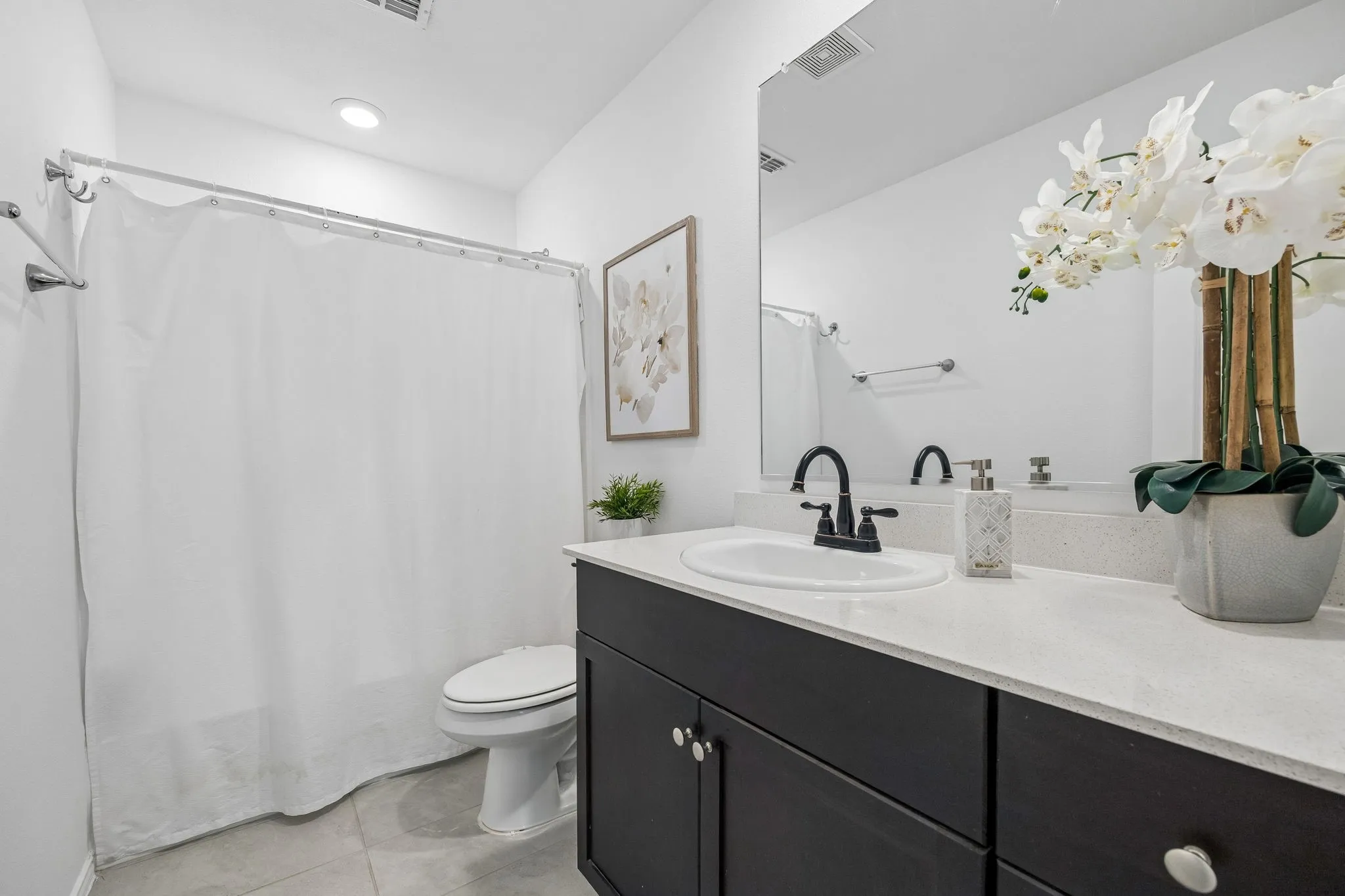 Contemporary bathroom featuring a dark wood-finish vanity with white countertop, an undermount sink, and a large wall-mounted mirror