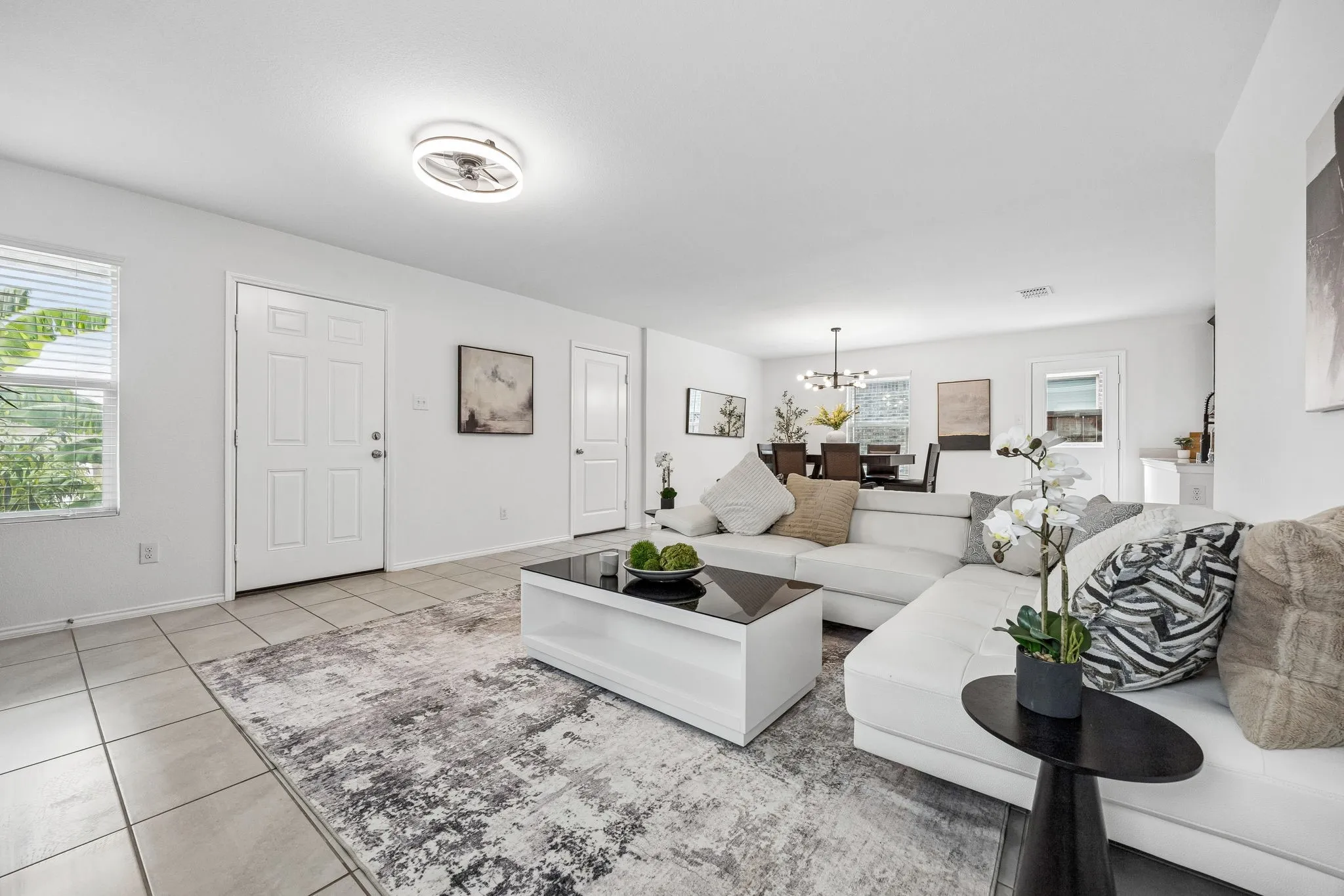Open-concept living space featuring light-toned tile flooring and a ceiling-mounted light fixture