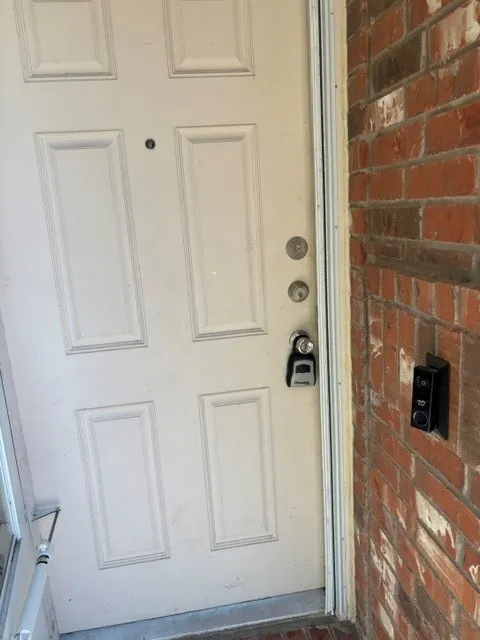 Brick exterior with a paneled entry door and a digital doorbell system