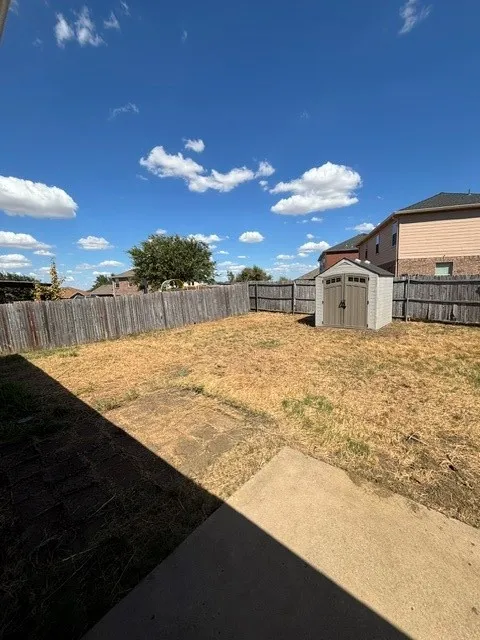 Fenced backyard with a storage shed and concrete patio
