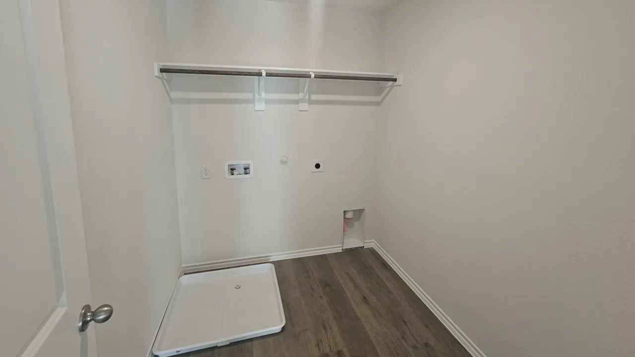 Laundry area with wood-finish flooring, light-toned walls, and a built-in hanging rod