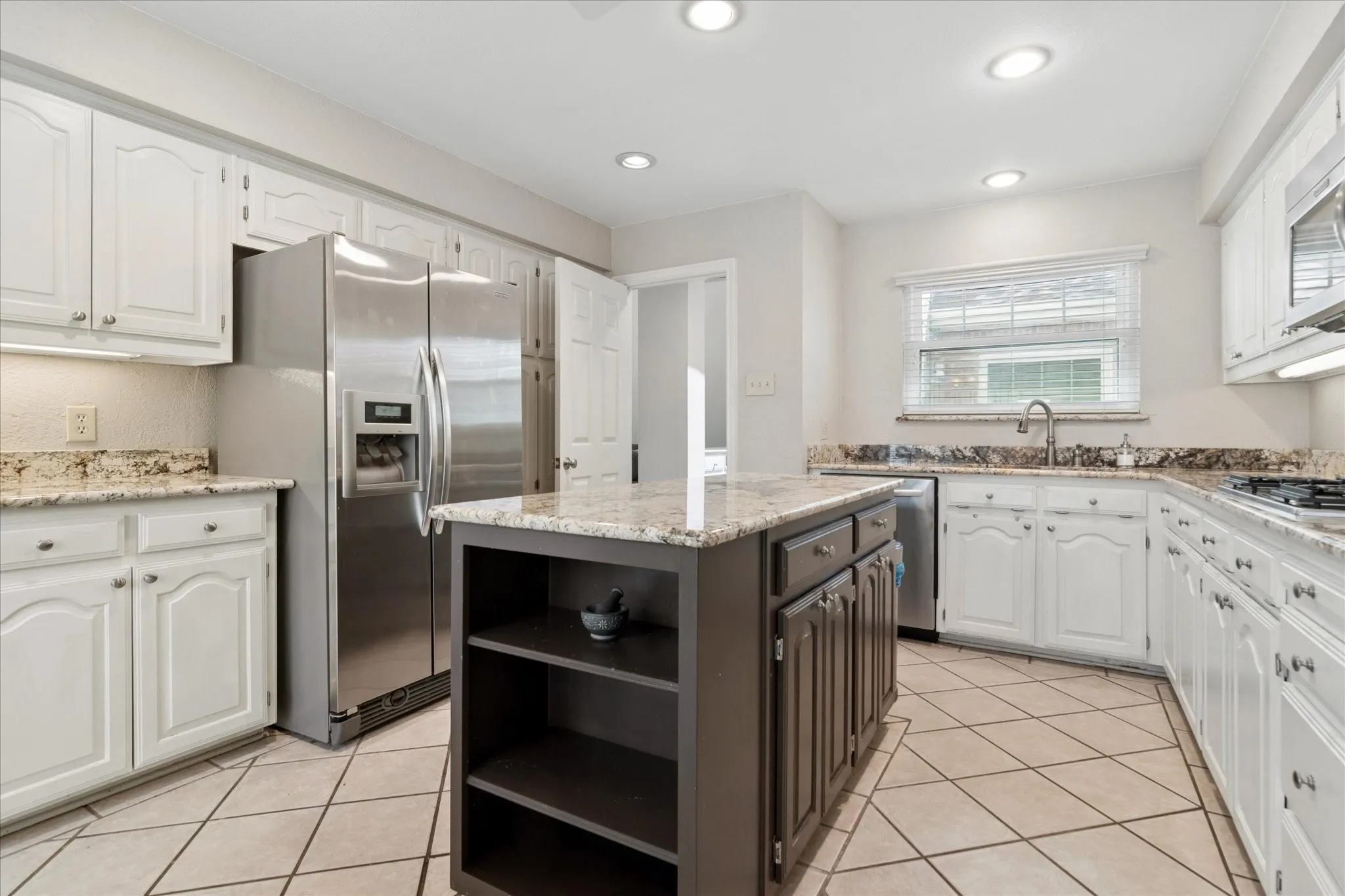 Granite countertops and lots of cabinetry, breakfast bar, and newer refrigerator featured in kitchen