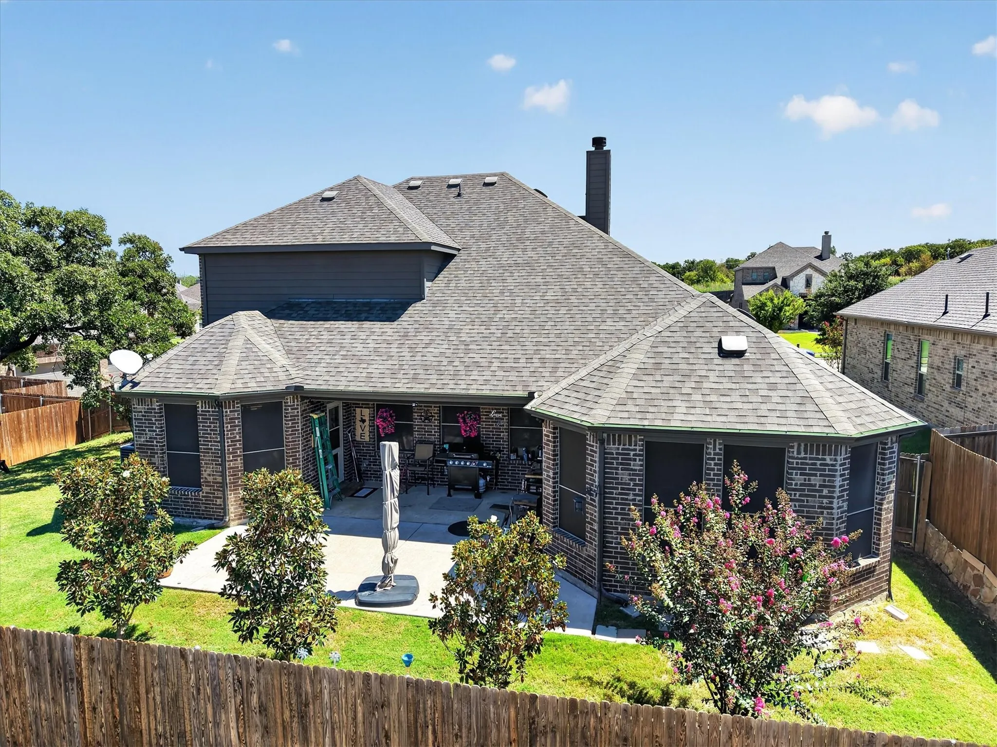 Expansive backyard featuring a manicured lawn, concrete patio, and mature landscaping