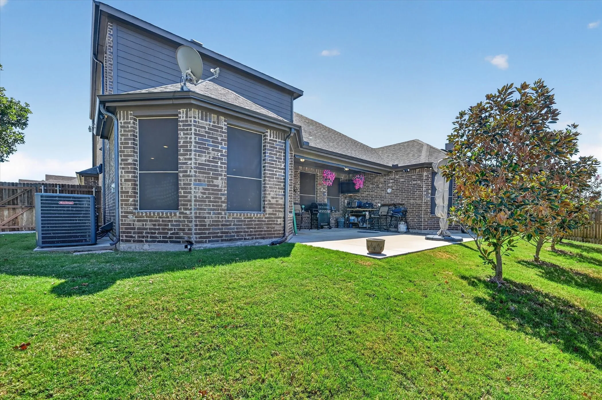 Expansive backyard with a covered patio, brick and siding exterior, and a privacy fence