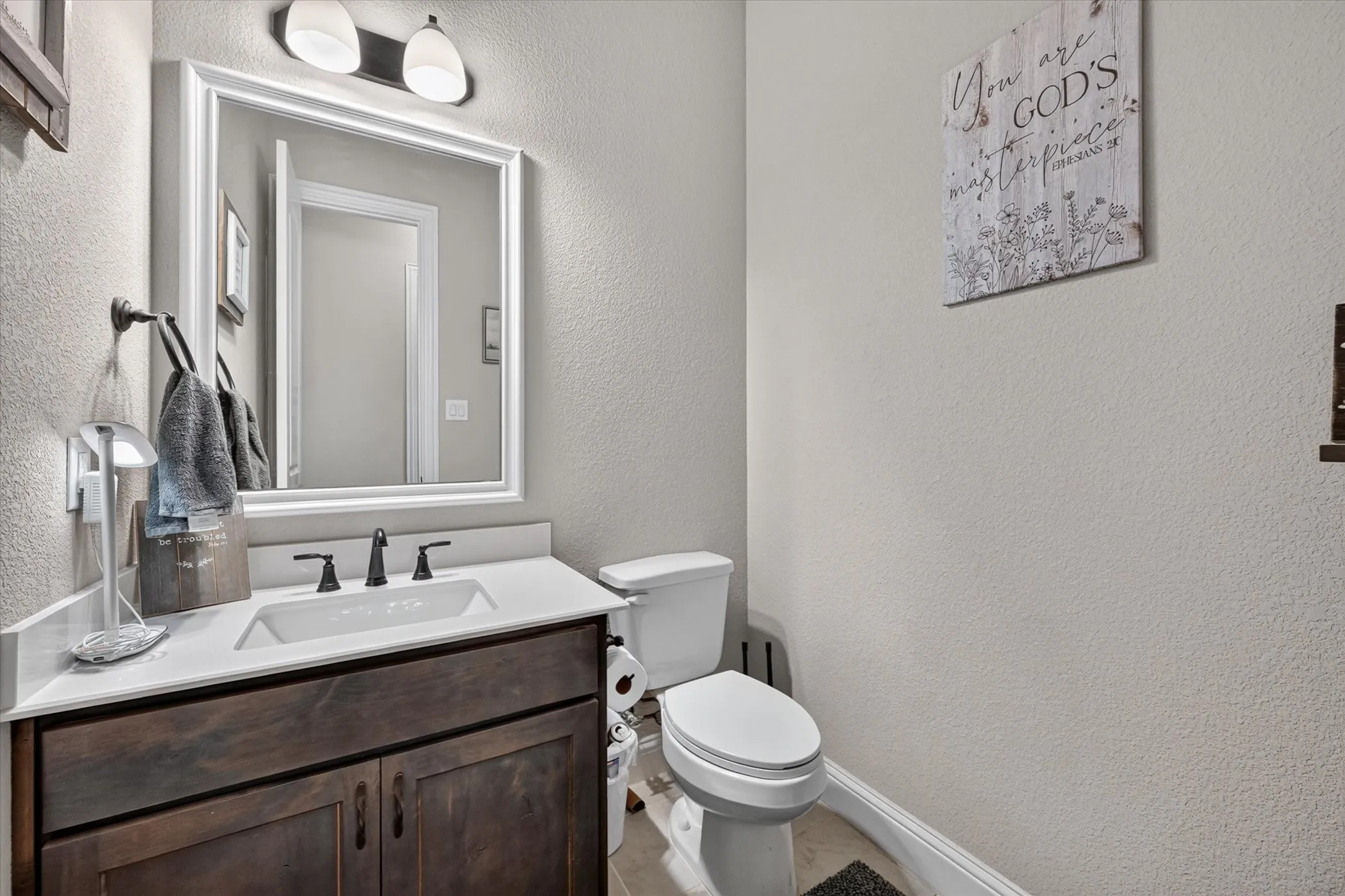 Built-in vanity with wood-finish cabinetry, white countertop, and rectangular undermount sink