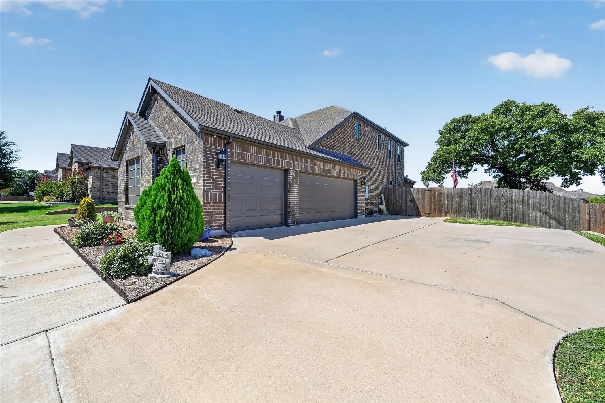Brick exterior, multi-car driveway, attached garage, well-maintained landscaping, and privacy fence