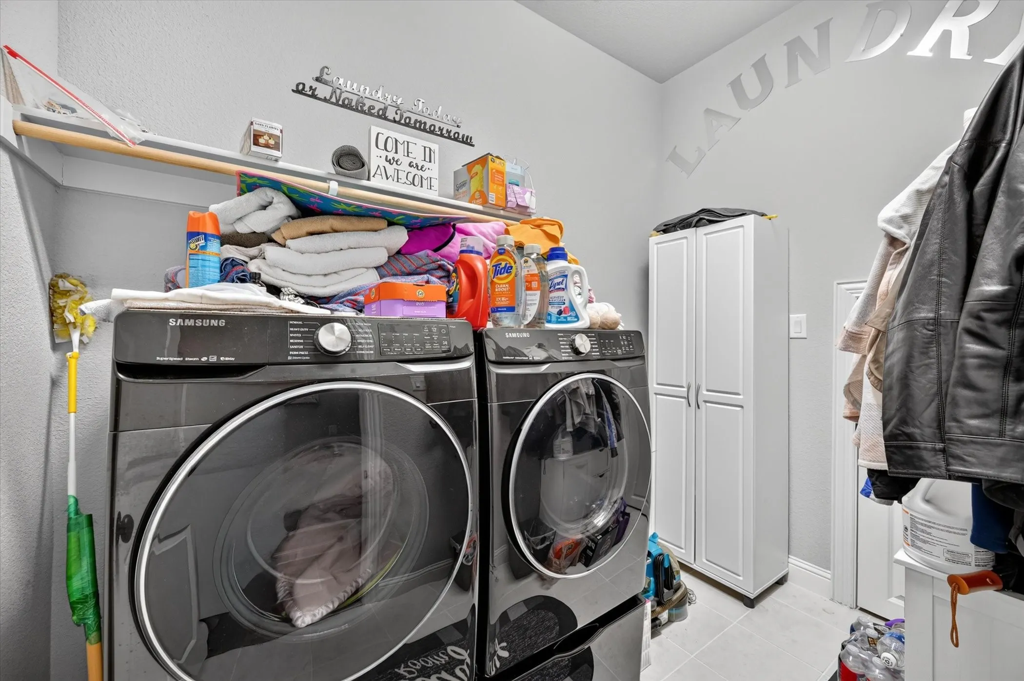 Utility room featuring a compact storage cabinet and light-toned tile flooring