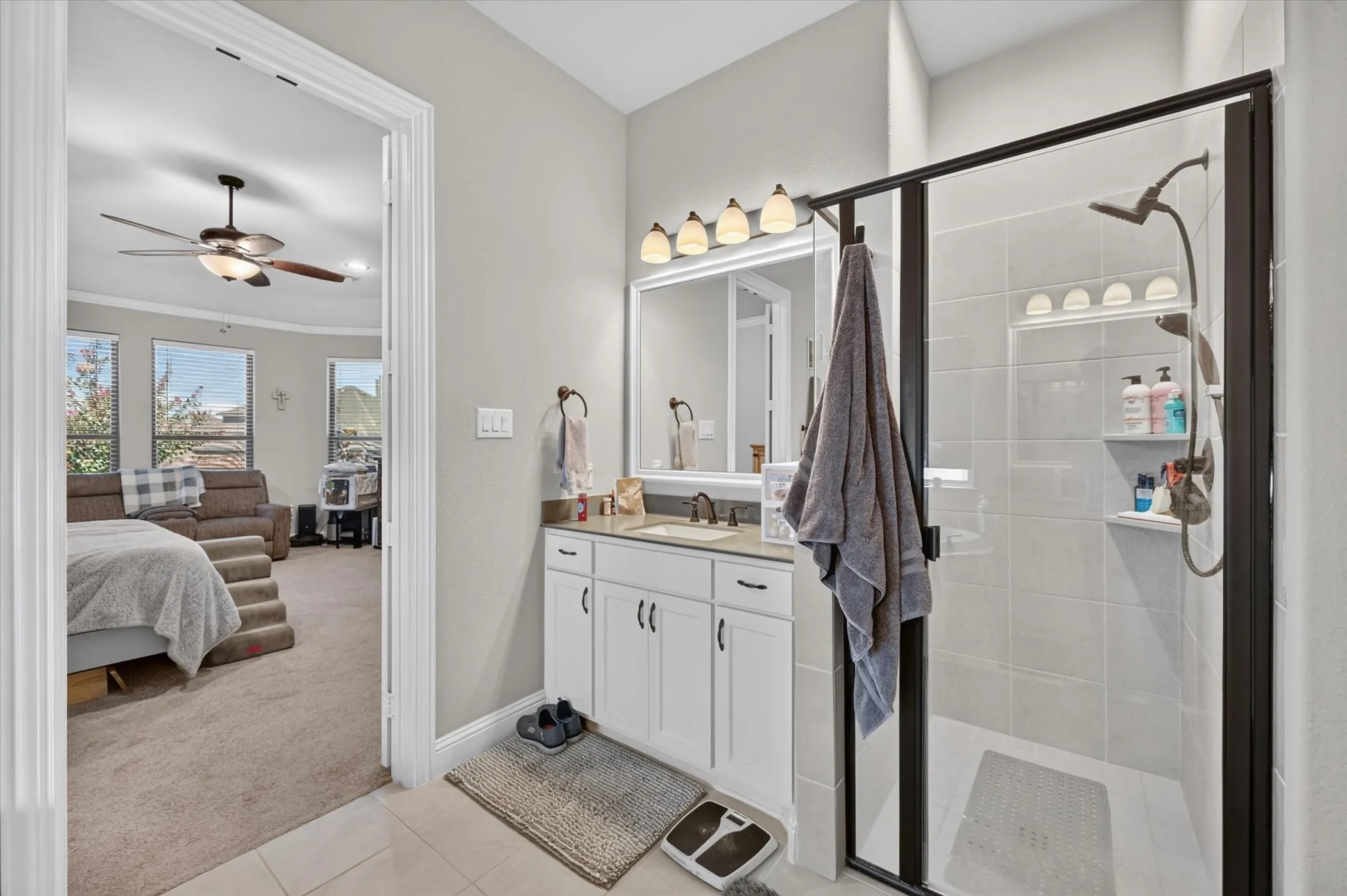 Walk-in shower with dark-framed glass enclosure, white tiled walls, and integrated shower shelves