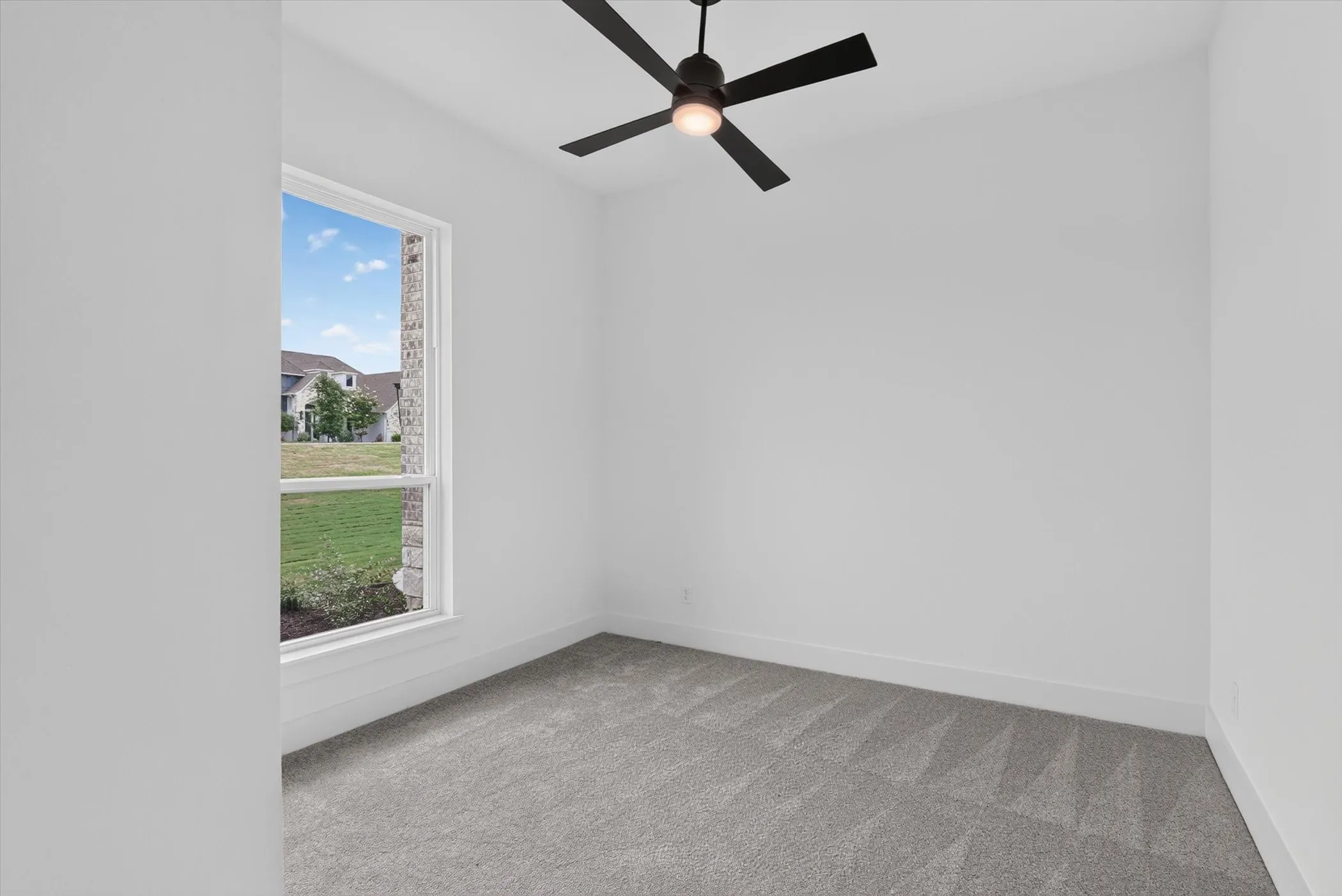 Room featuring a single-pane window, neutral carpet flooring, white walls, and a ceiling fan with integrated lighting
