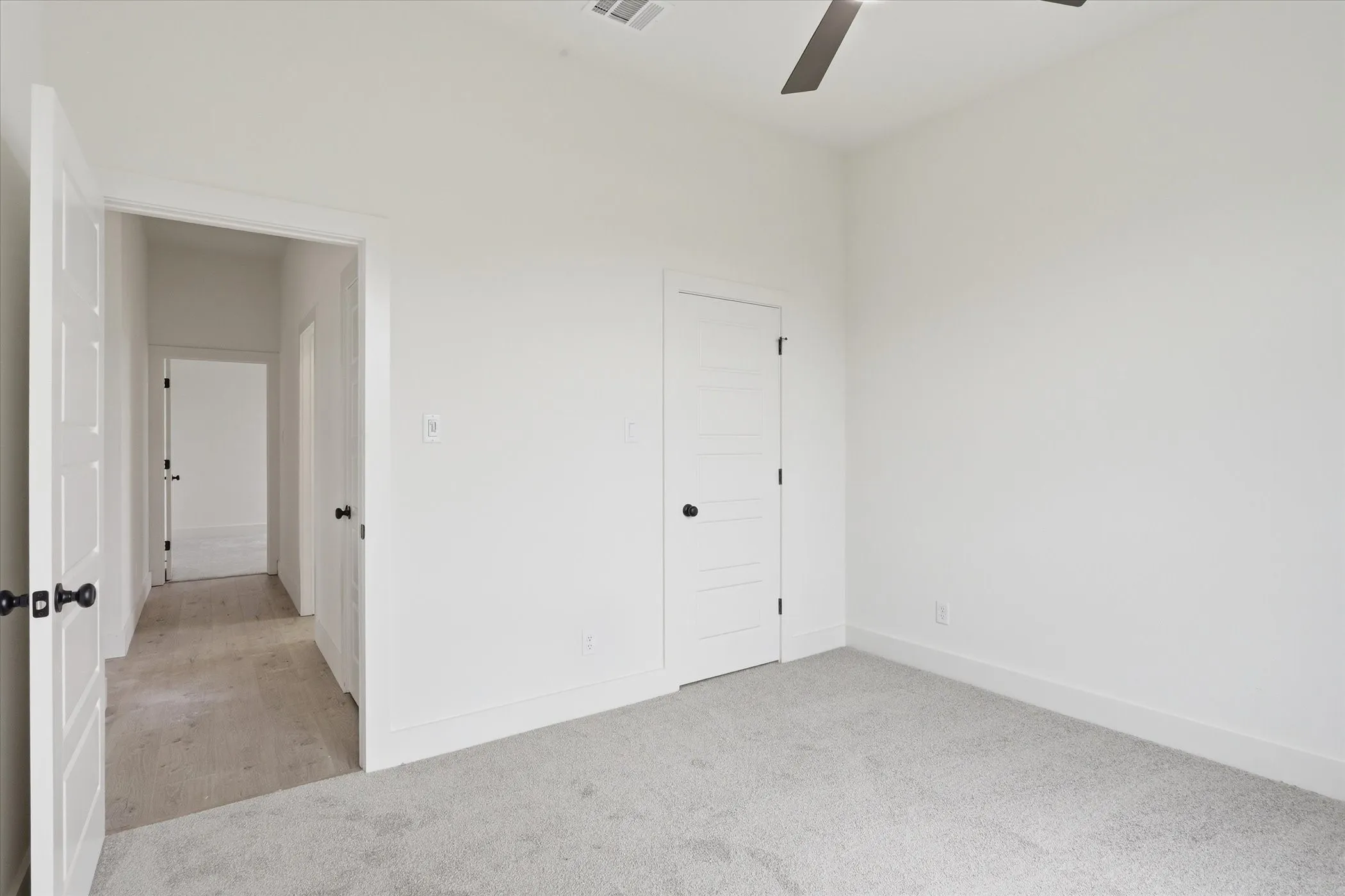 Bedroom featuring light gray carpet, crisp white walls, and a contemporary ceiling fan