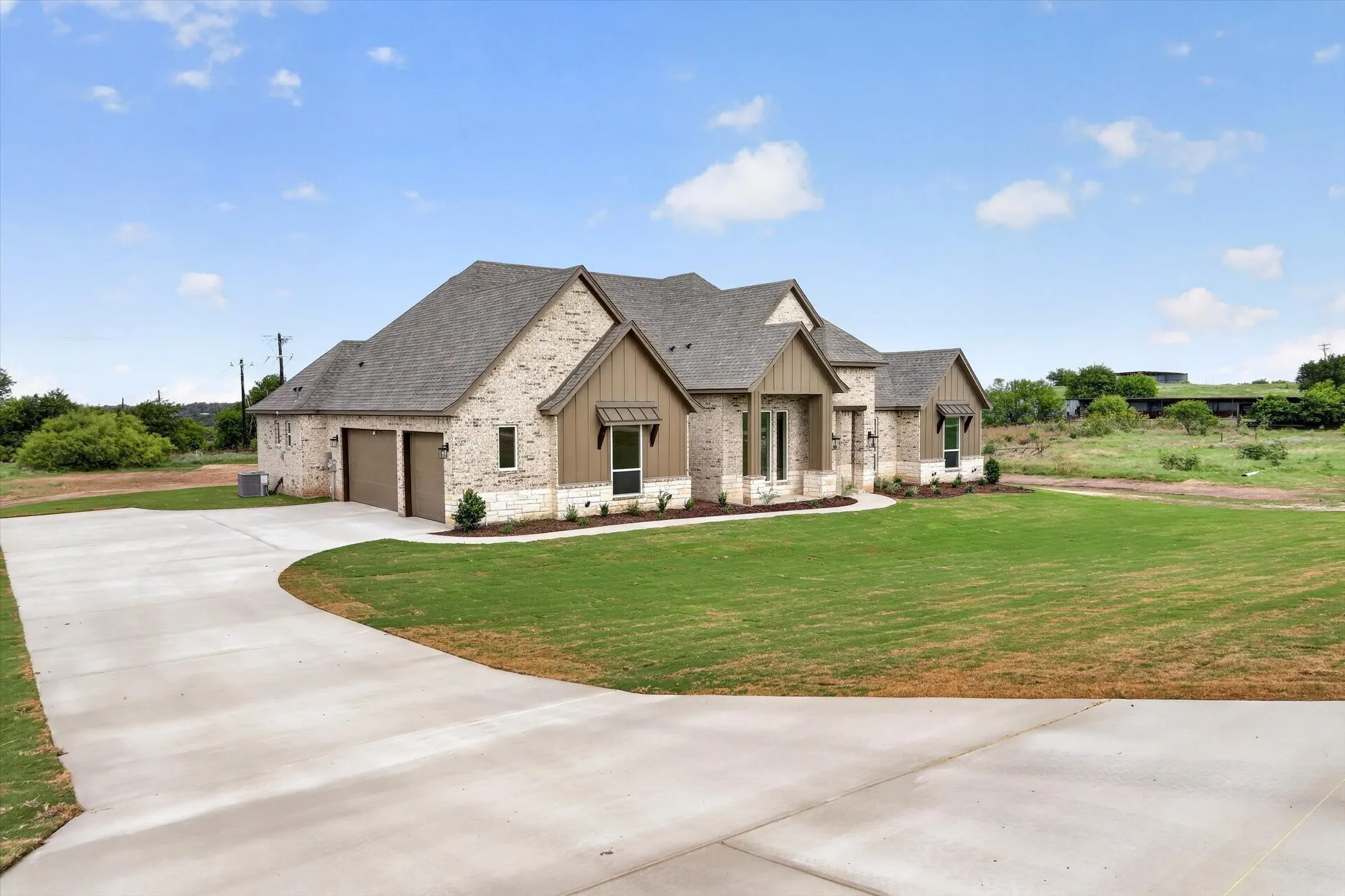 Single-story residence featuring a brick and stone facade, a multi-gabled roofline, and a two-car attached garage