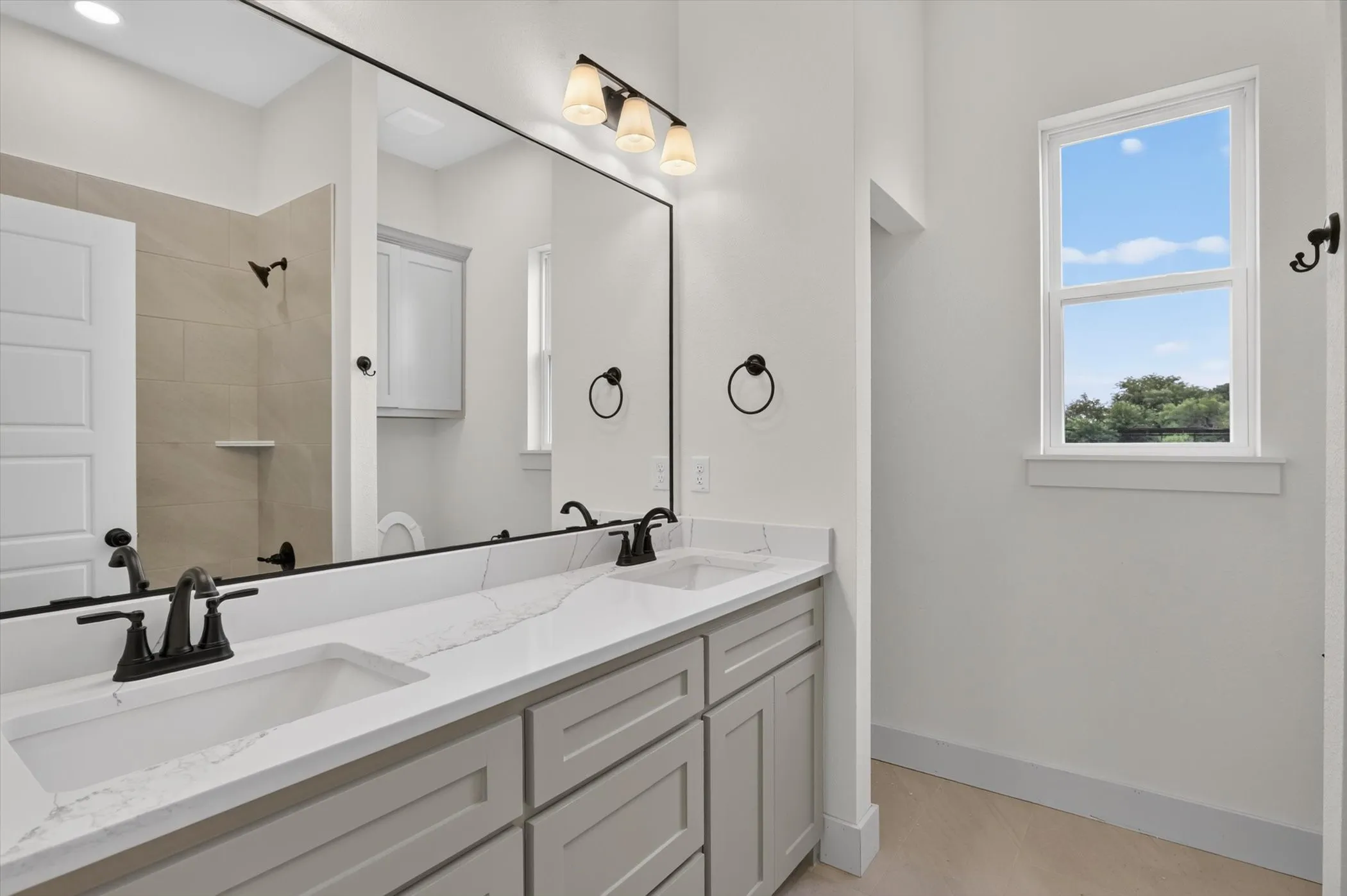 Double vanity with integrated rectangular sinks, white stone countertop with veining, and matte black fixtures