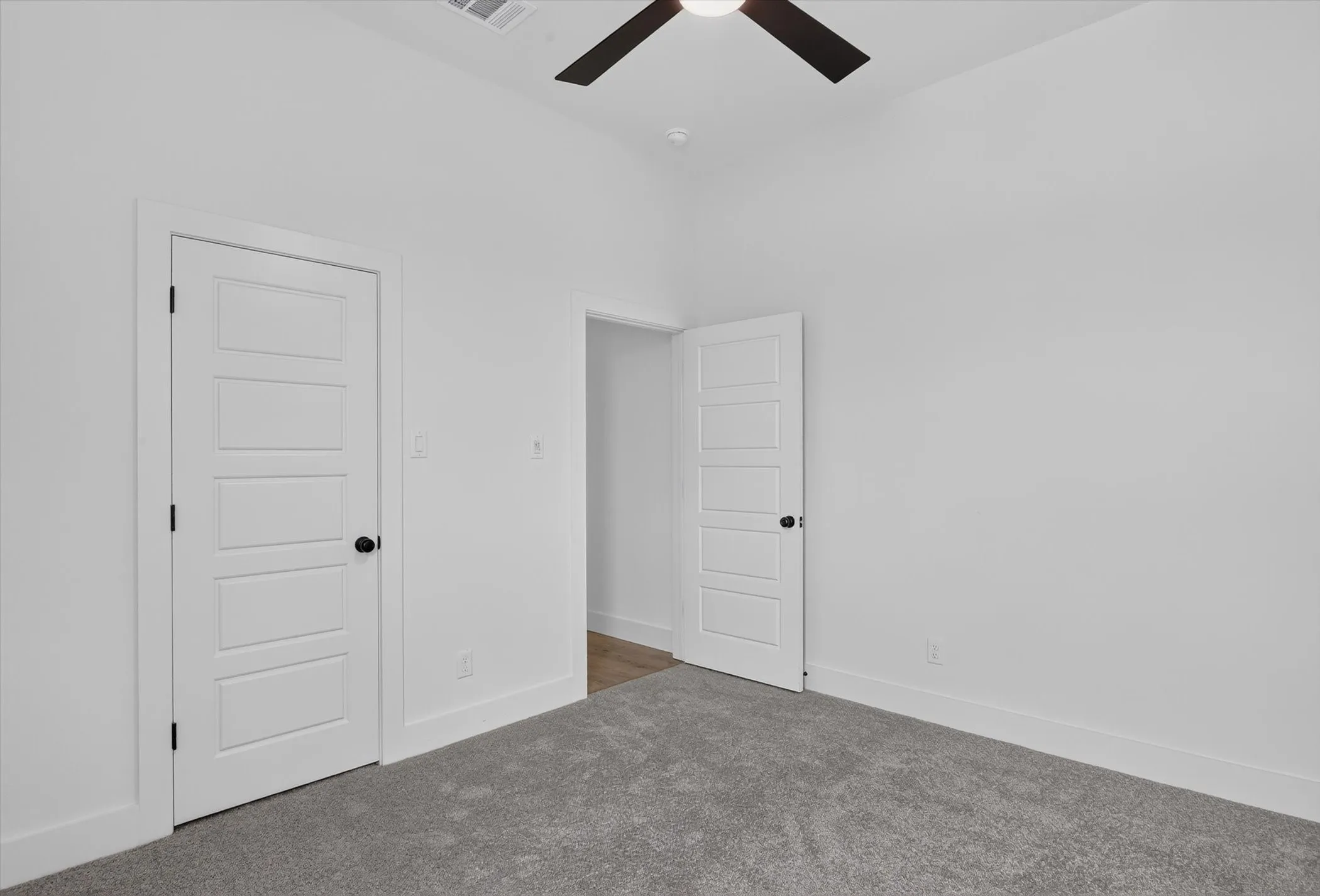 Spacious room featuring vaulted ceilings, a ceiling fan with integrated lighting, and light grey carpeting