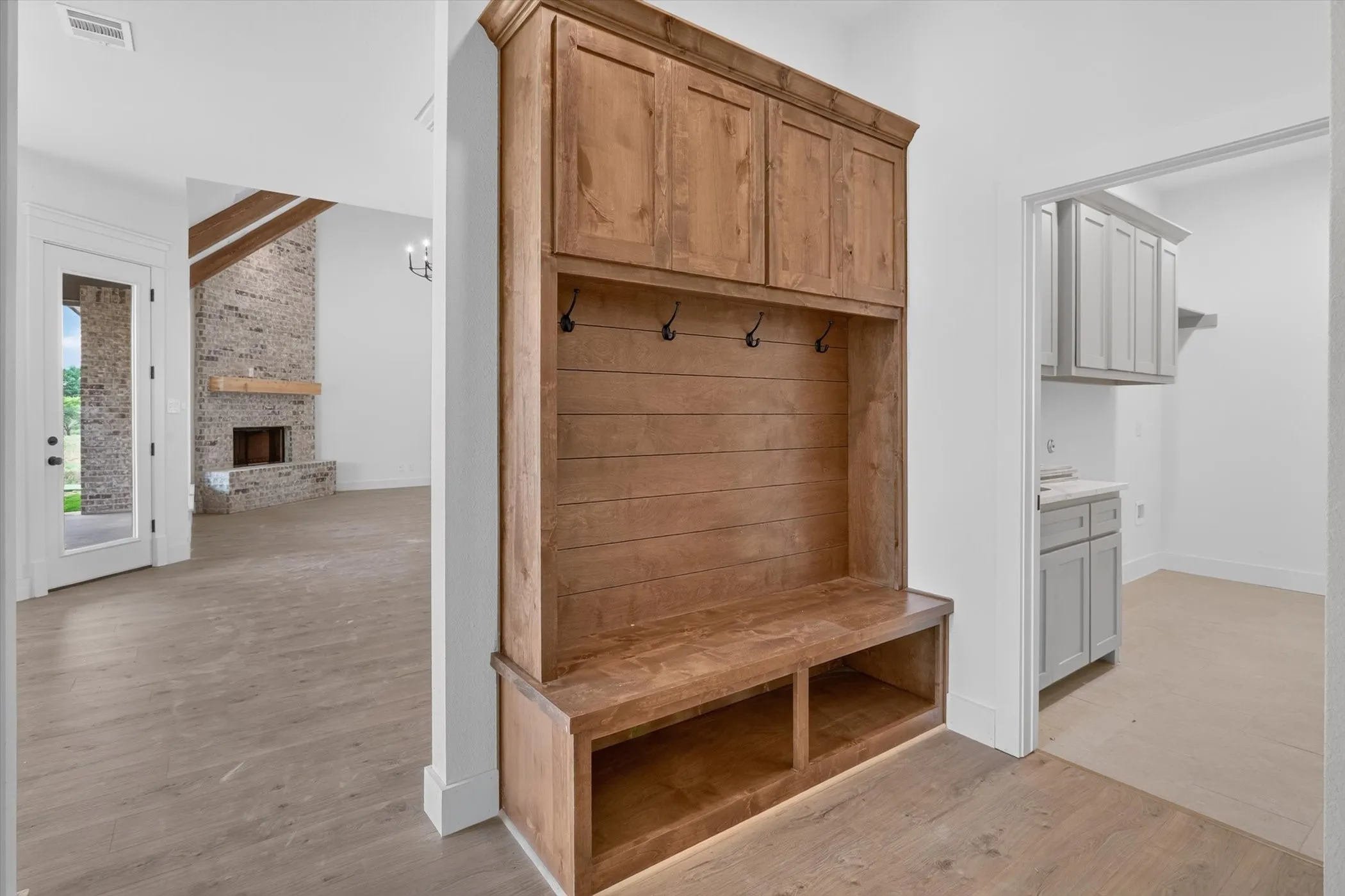 Built-in wood-finish hall tree with upper cabinetry, storage bench, and coat hooks