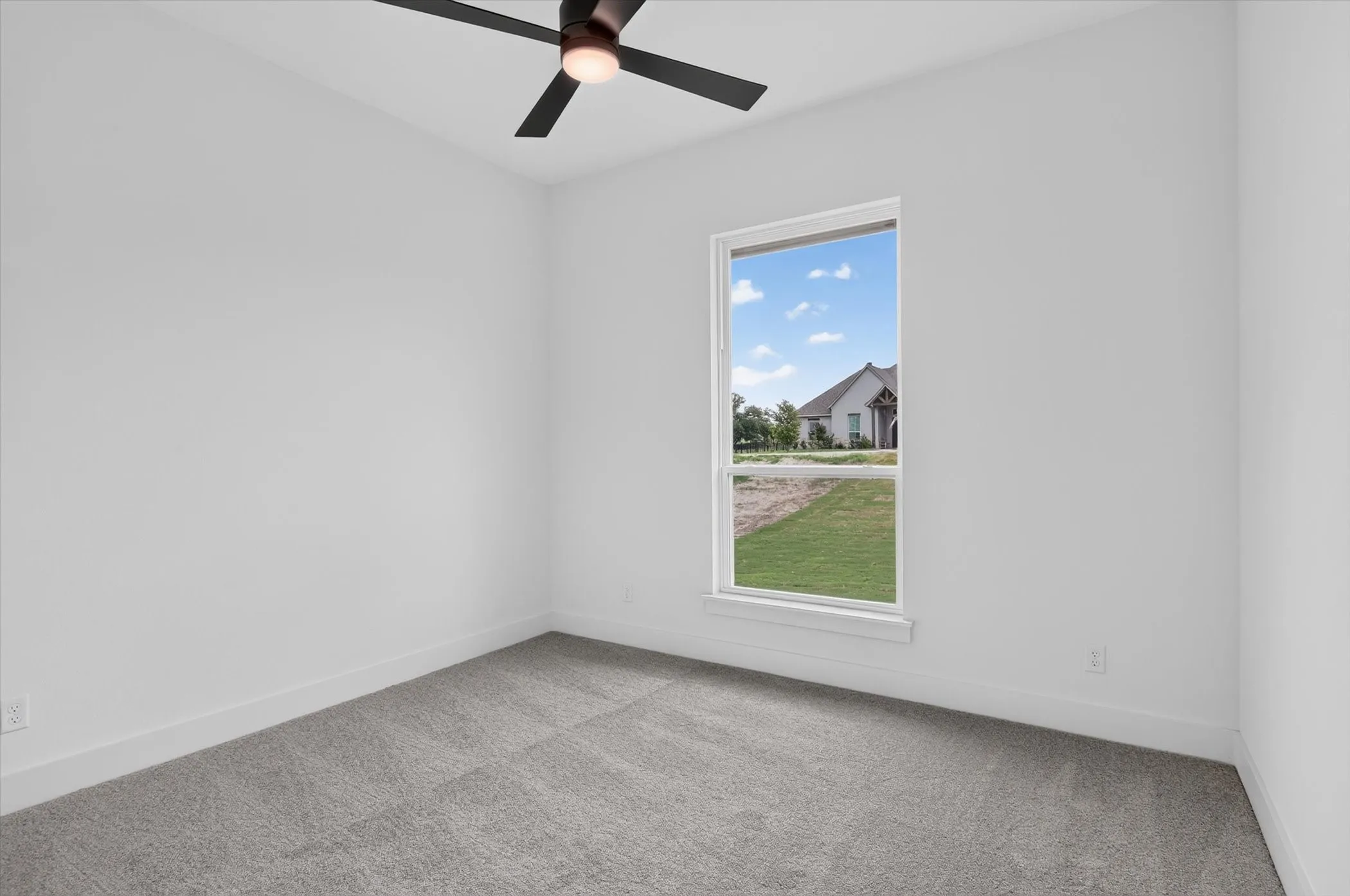 Carpeted room featuring a ceiling fan with integrated lighting, a large window, white baseboards, and neutral wall tones