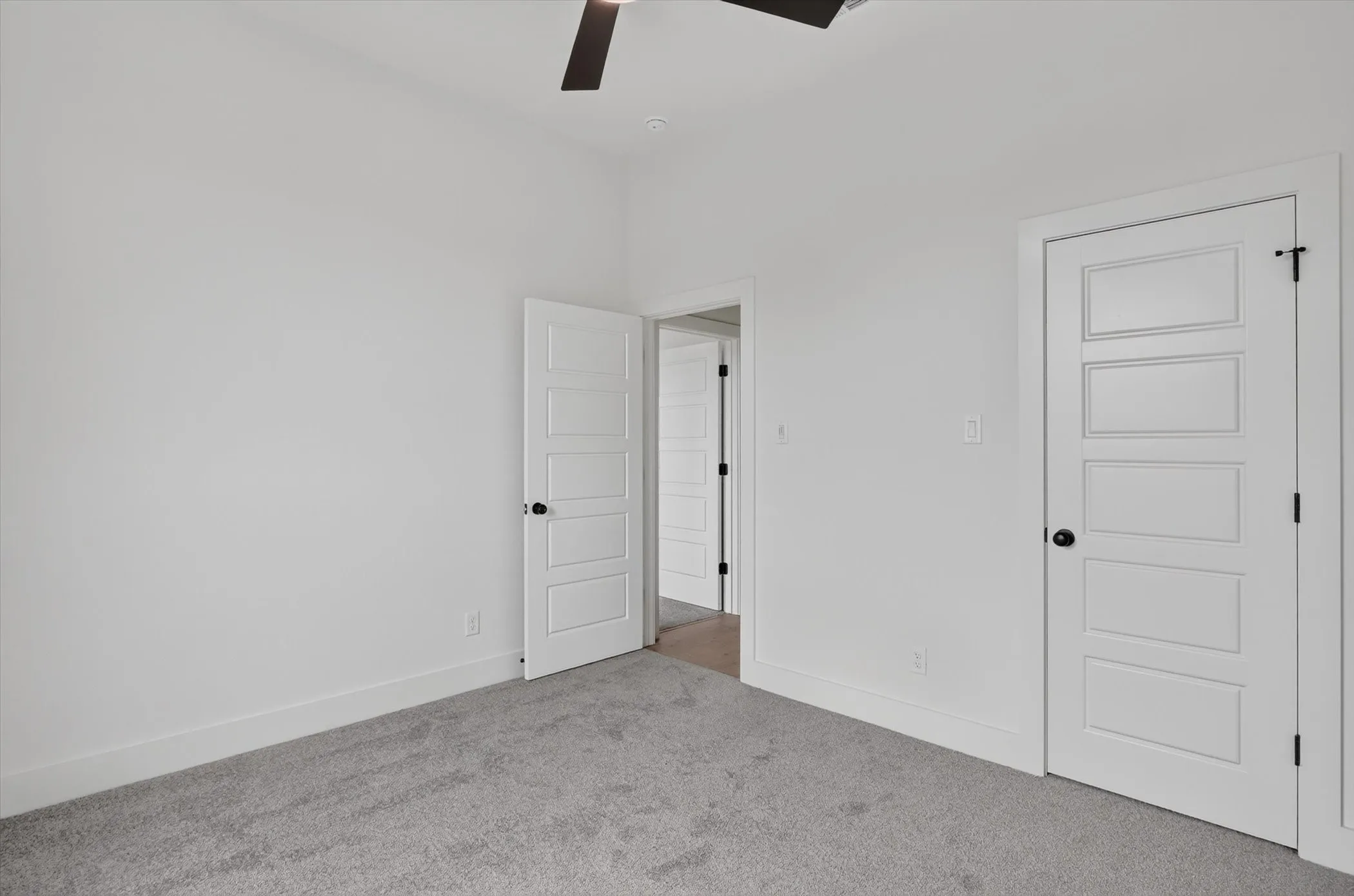 Interior room featuring light gray carpet flooring, white walls, and white five-panel doors