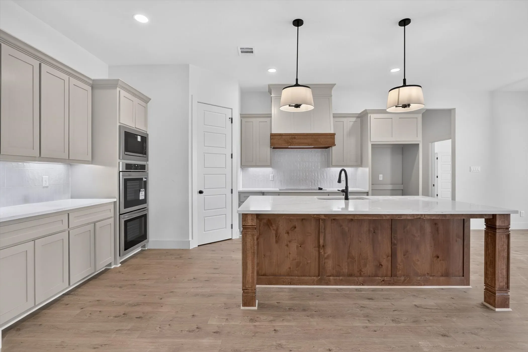 Expansive kitchen featuring a large wood-finish island with a light-toned countertop, complete with an undermount sink and matte black faucet