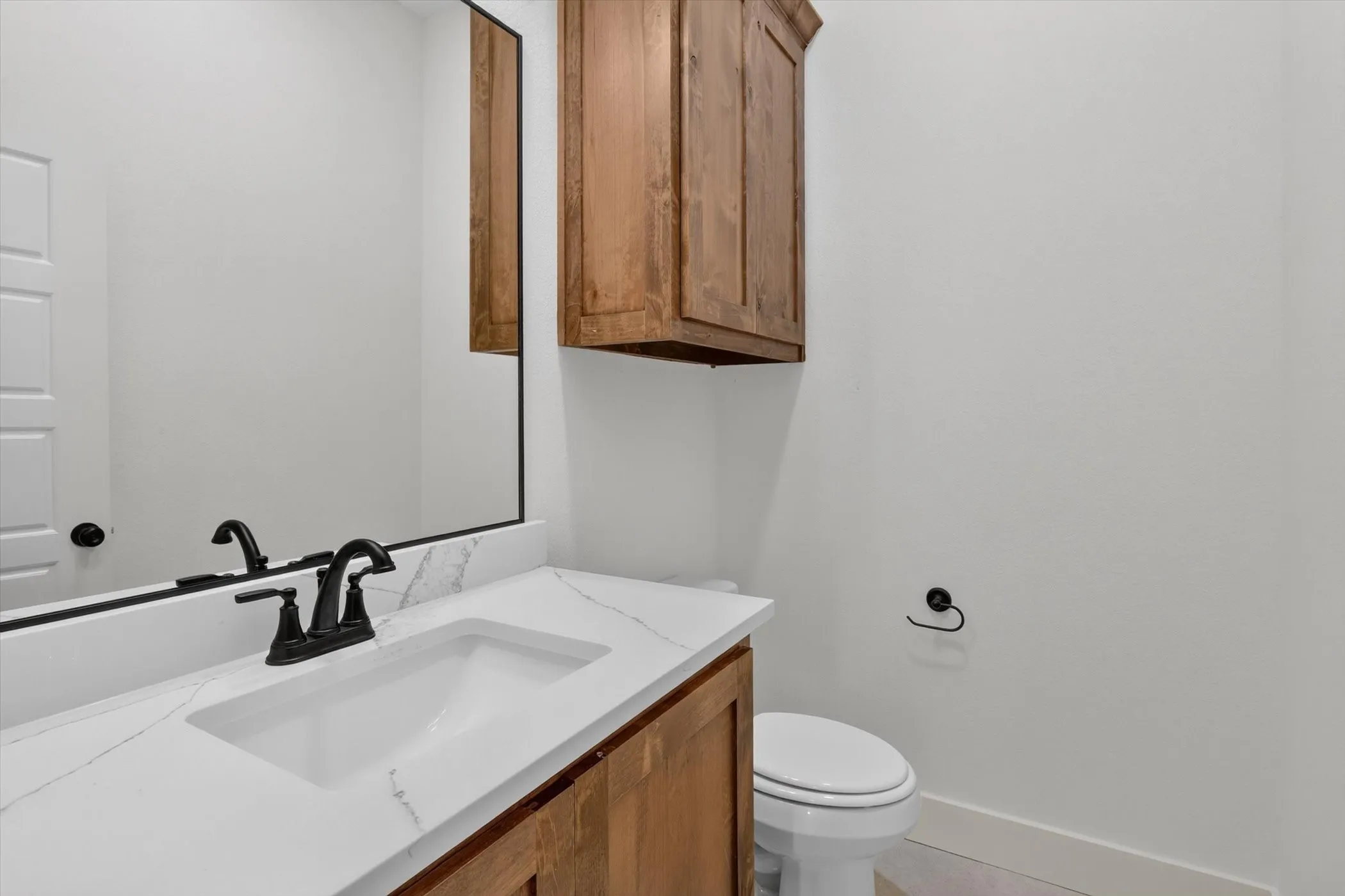 White vanity with an integrated rectangular sink, stone-finish countertop, matte black faucet, and coordinating hardware
