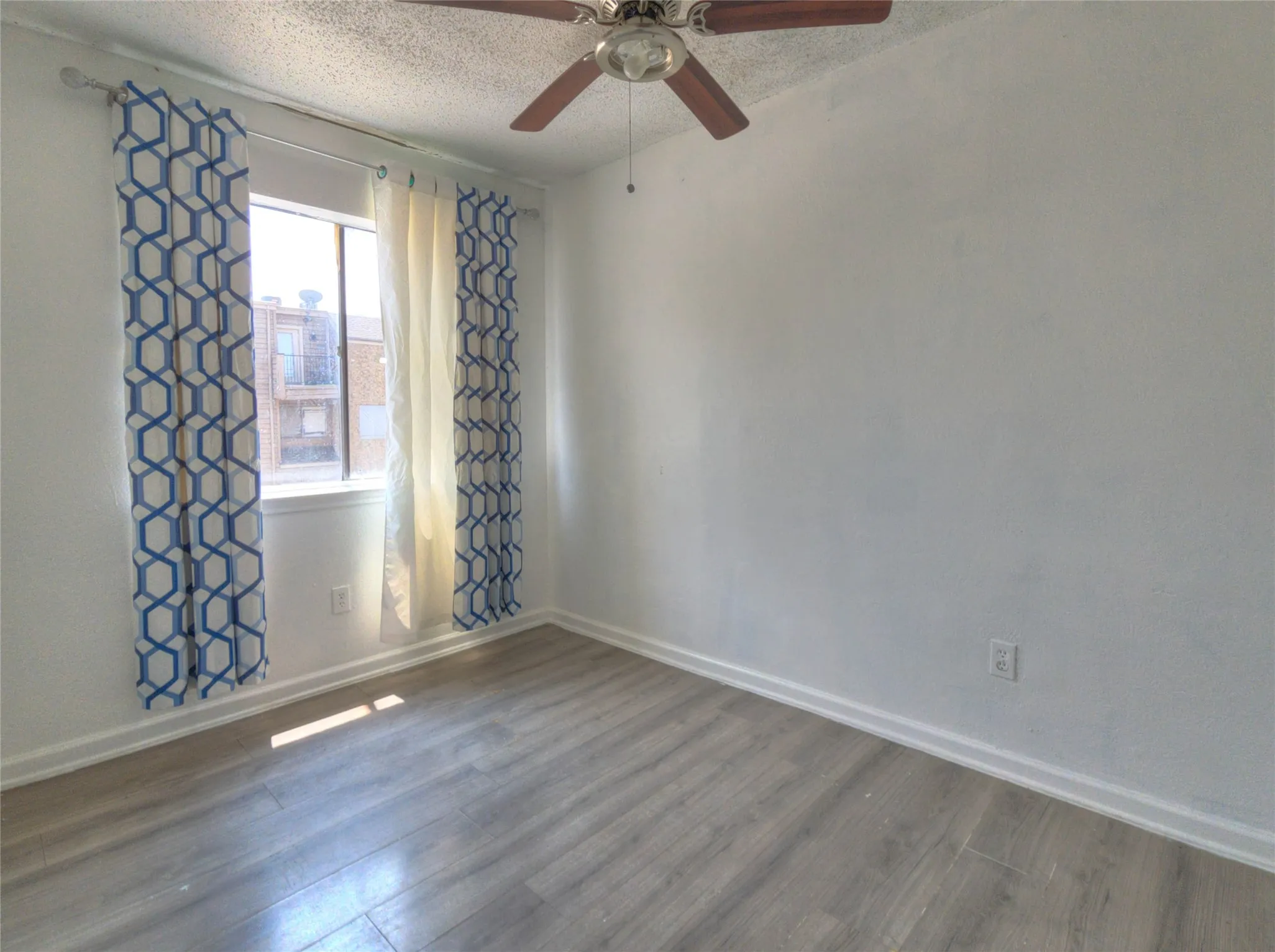 Recessed window with natural light, wood-finish flooring, and a ceiling fan