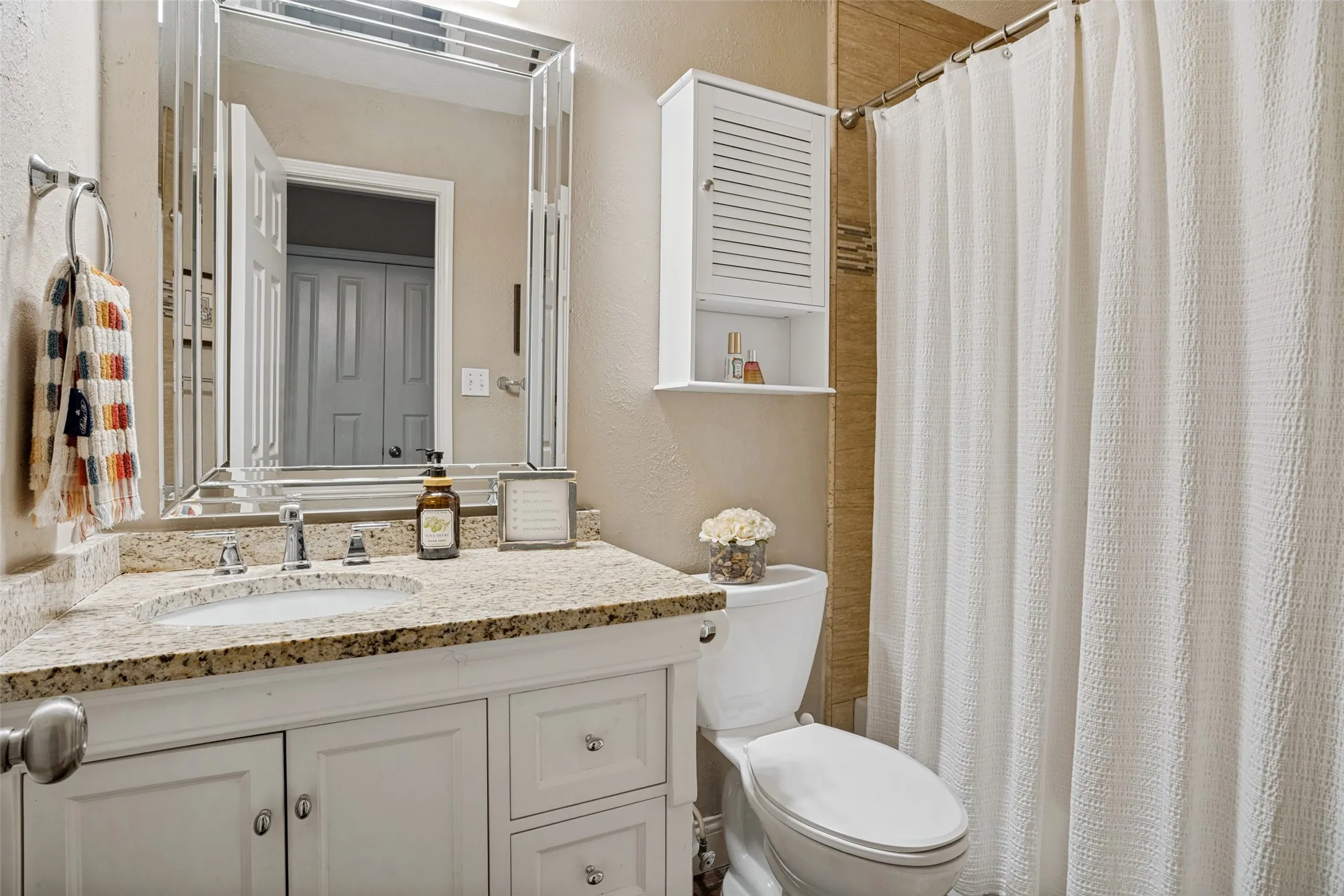 The secondary bathroom has been updated with a granite topped vanity, a pretty mirror & updated tile surround in the shower.