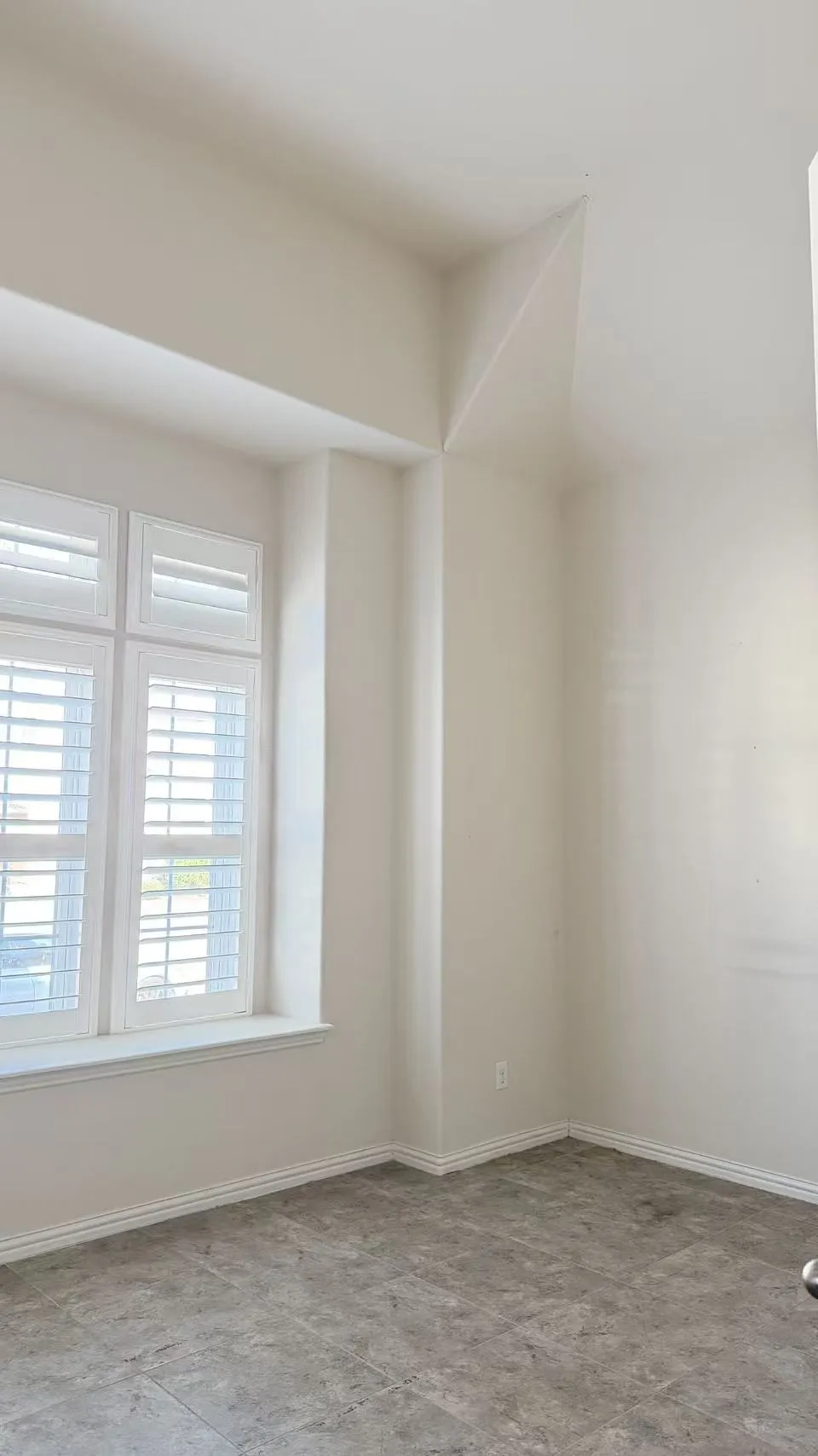 Recessed window with plantation shutters, tiled flooring, and neutral wall tones