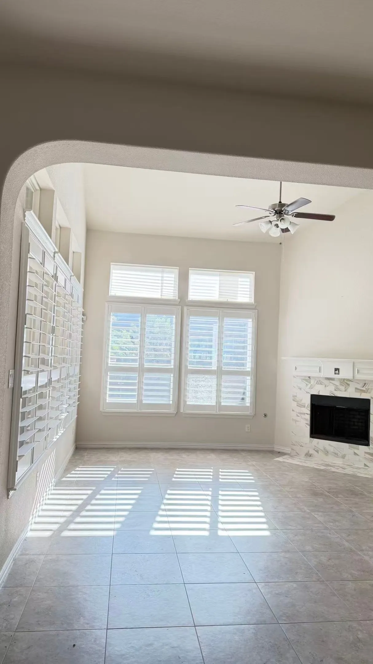 Bright and airy great room flooded with natural light through dual French doors featuring multiple panes and plantation shutters