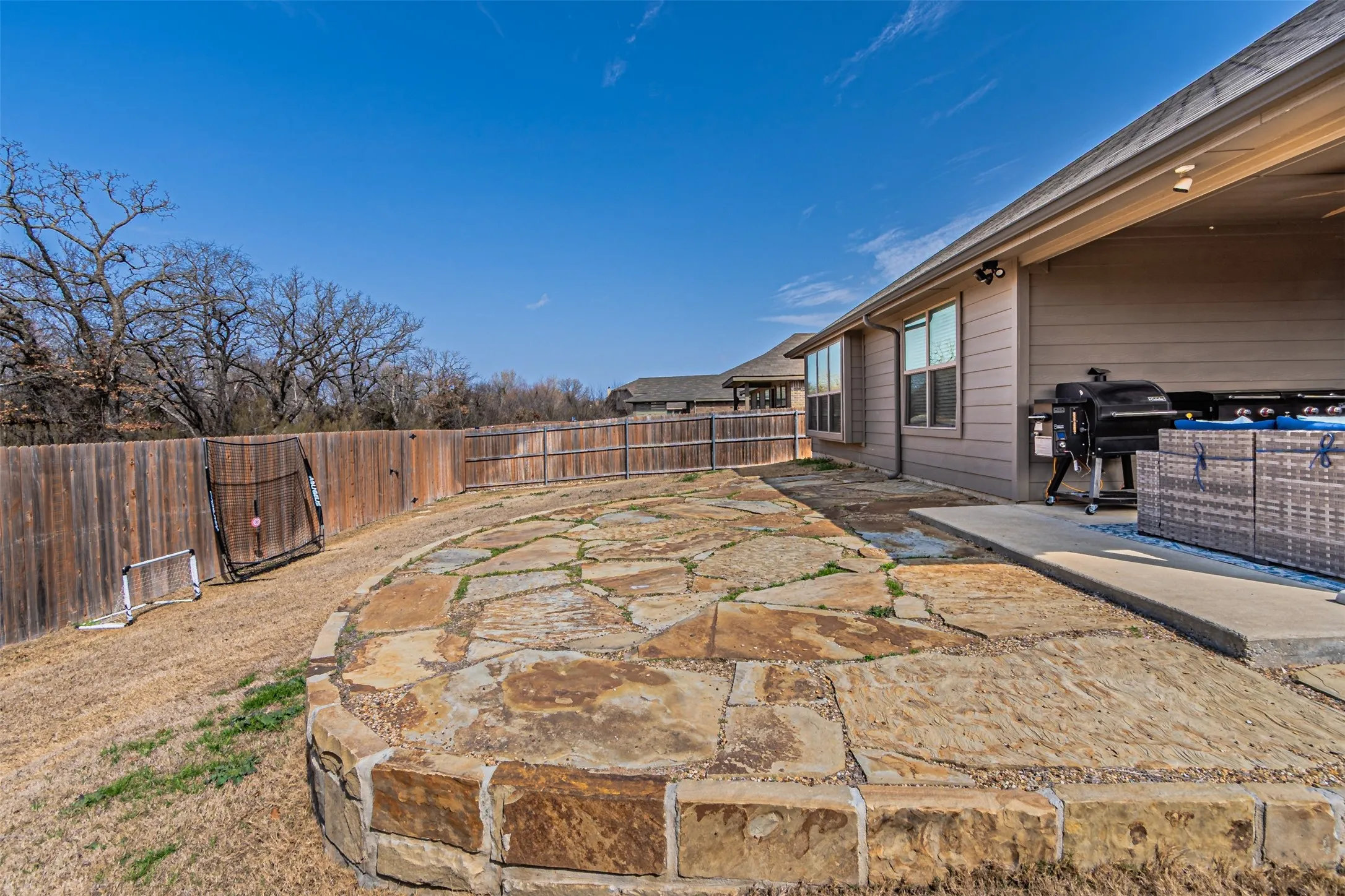 Fenced backyard featuring a patio and a grill
