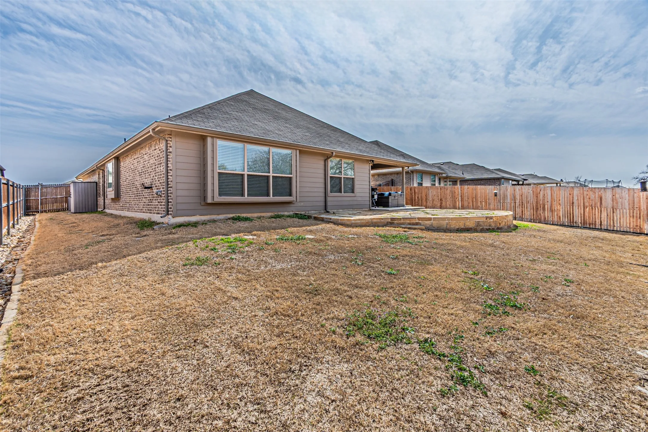 Back of property with a fenced backyard, a patio area, and brick siding