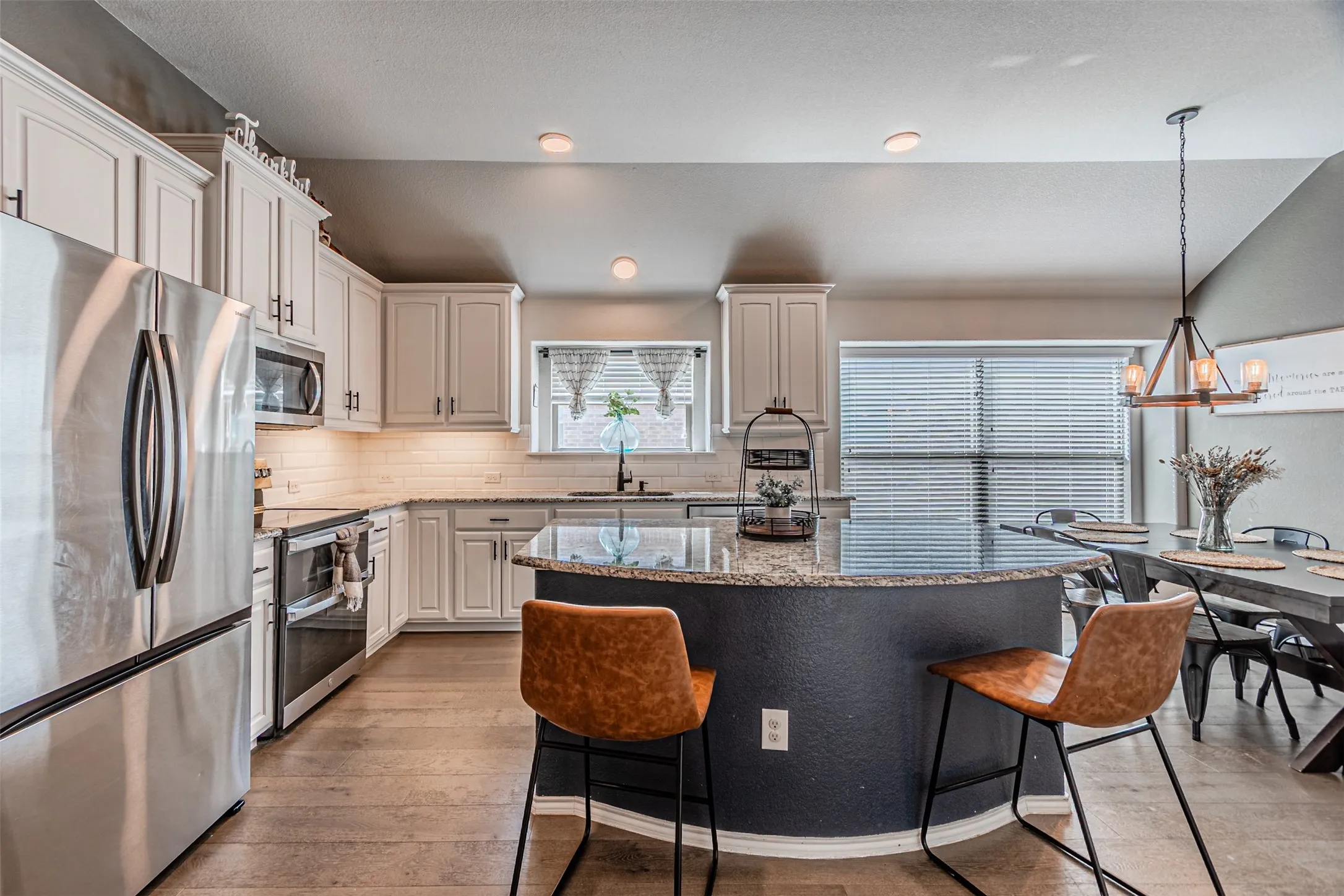 Kitchen featuring stainless steel appliances, light stone countertops, a kitchen breakfast bar, lofted ceiling, and light wood-style floors