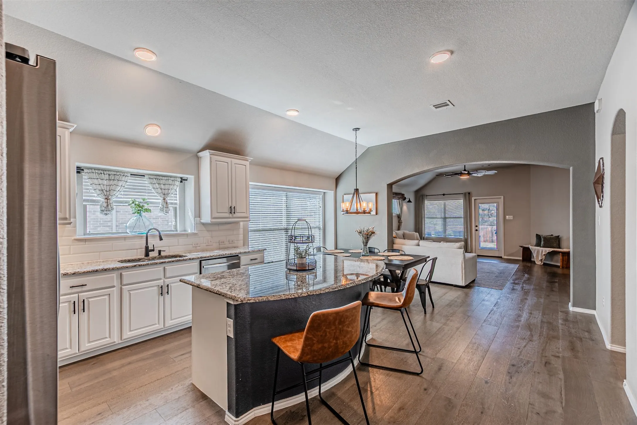 Kitchen with light stone countertops, tasteful backsplash, a kitchen breakfast bar, and white cabinetry
