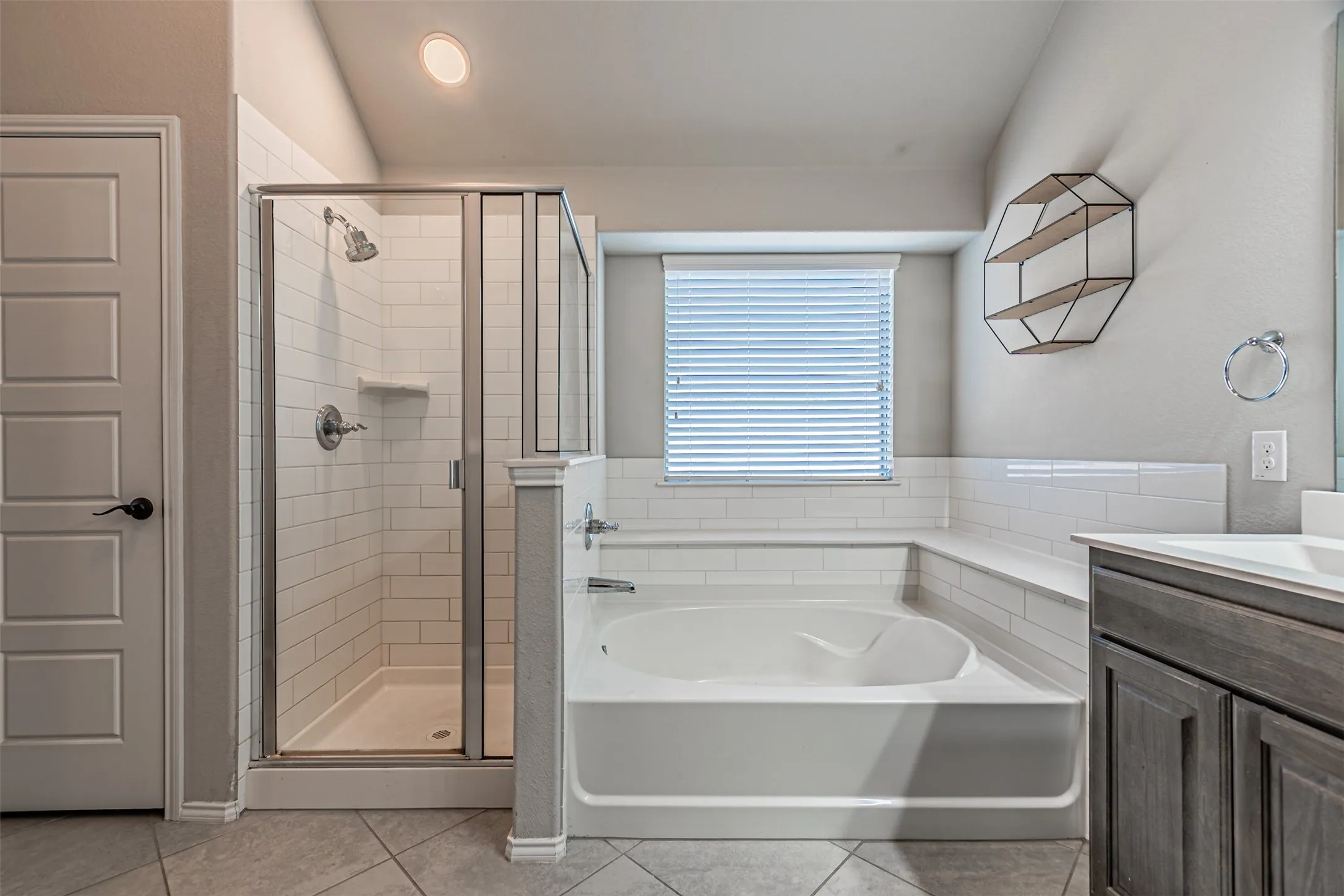 Bathroom with a garden tub, a stall shower, vanity, and light tile patterned flooring