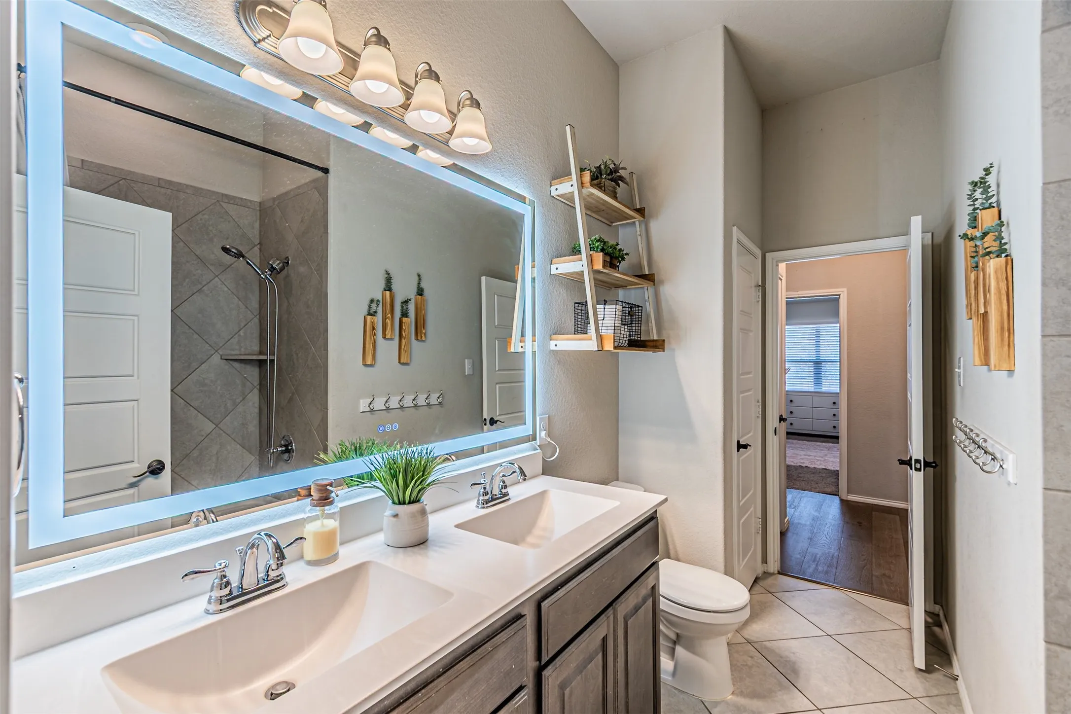 Full bathroom featuring double vanity, light tile patterned floors, and a shower
