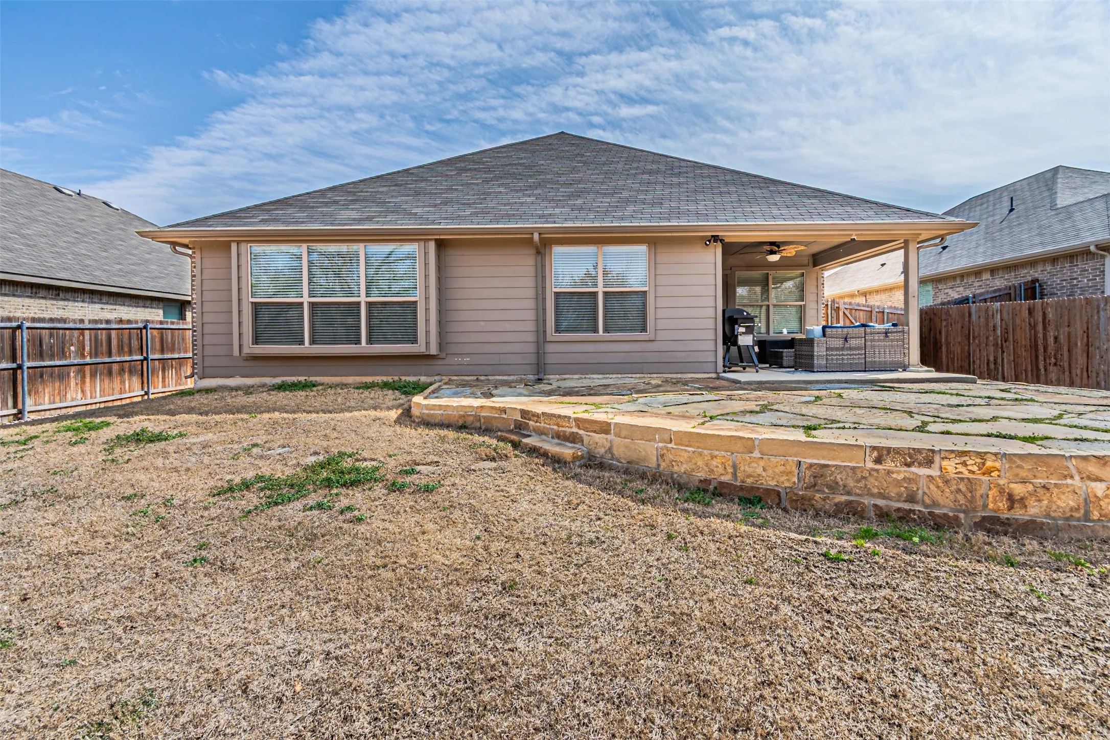 Back of property featuring a fenced backyard, a patio area, a ceiling fan, a shingled roof, and an outdoor living space