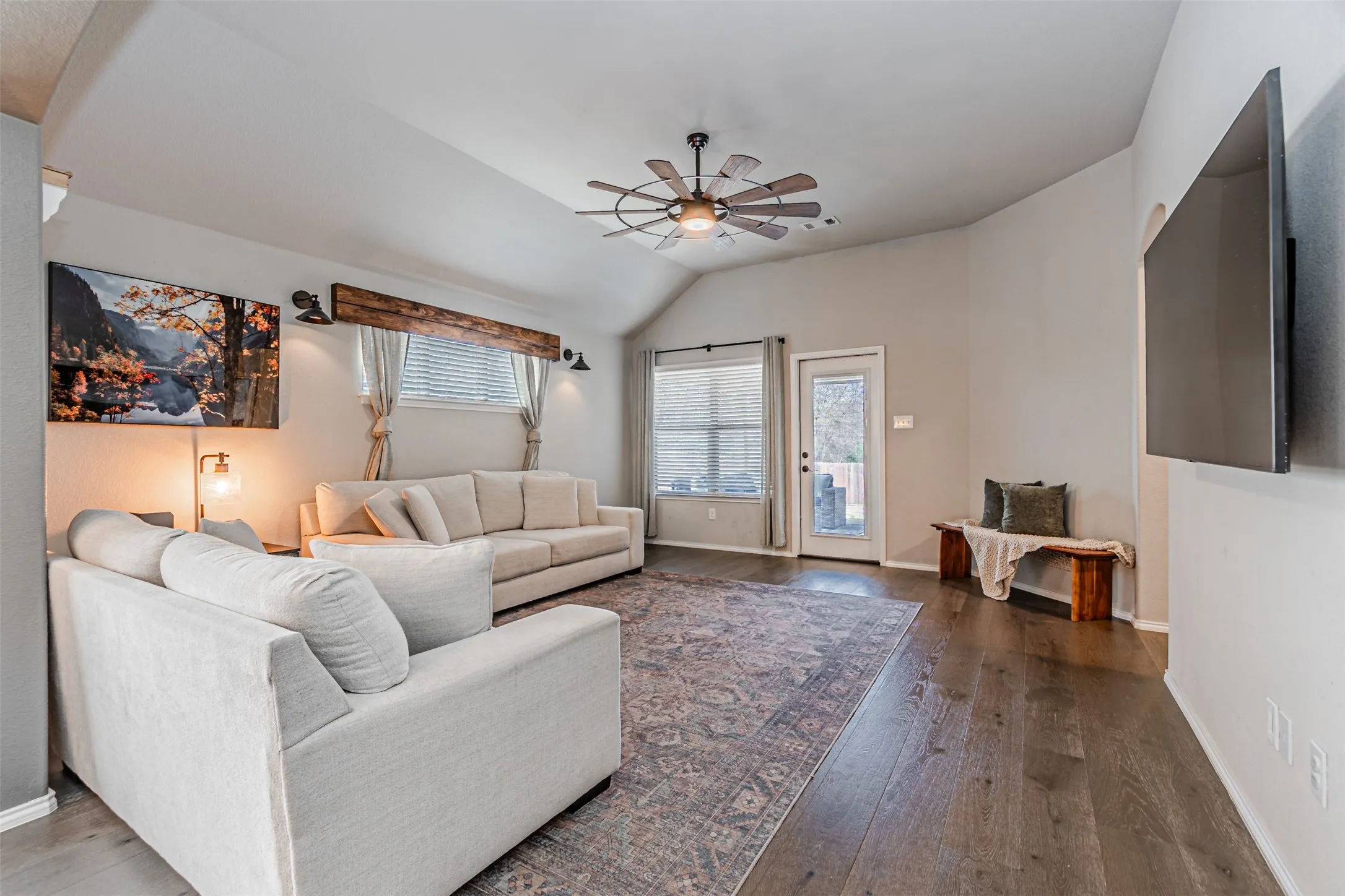 Living area with ceiling fan, vaulted ceiling, and hardwood / wood-style floors
