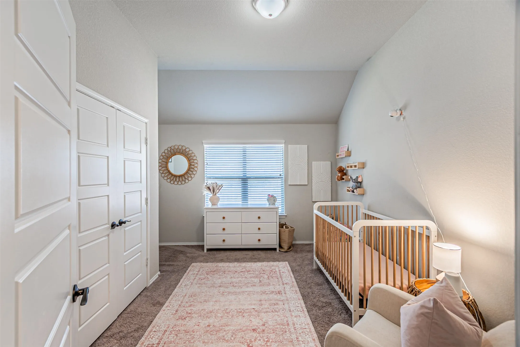 Bedroom with carpet, lofted ceiling, and a nursery area