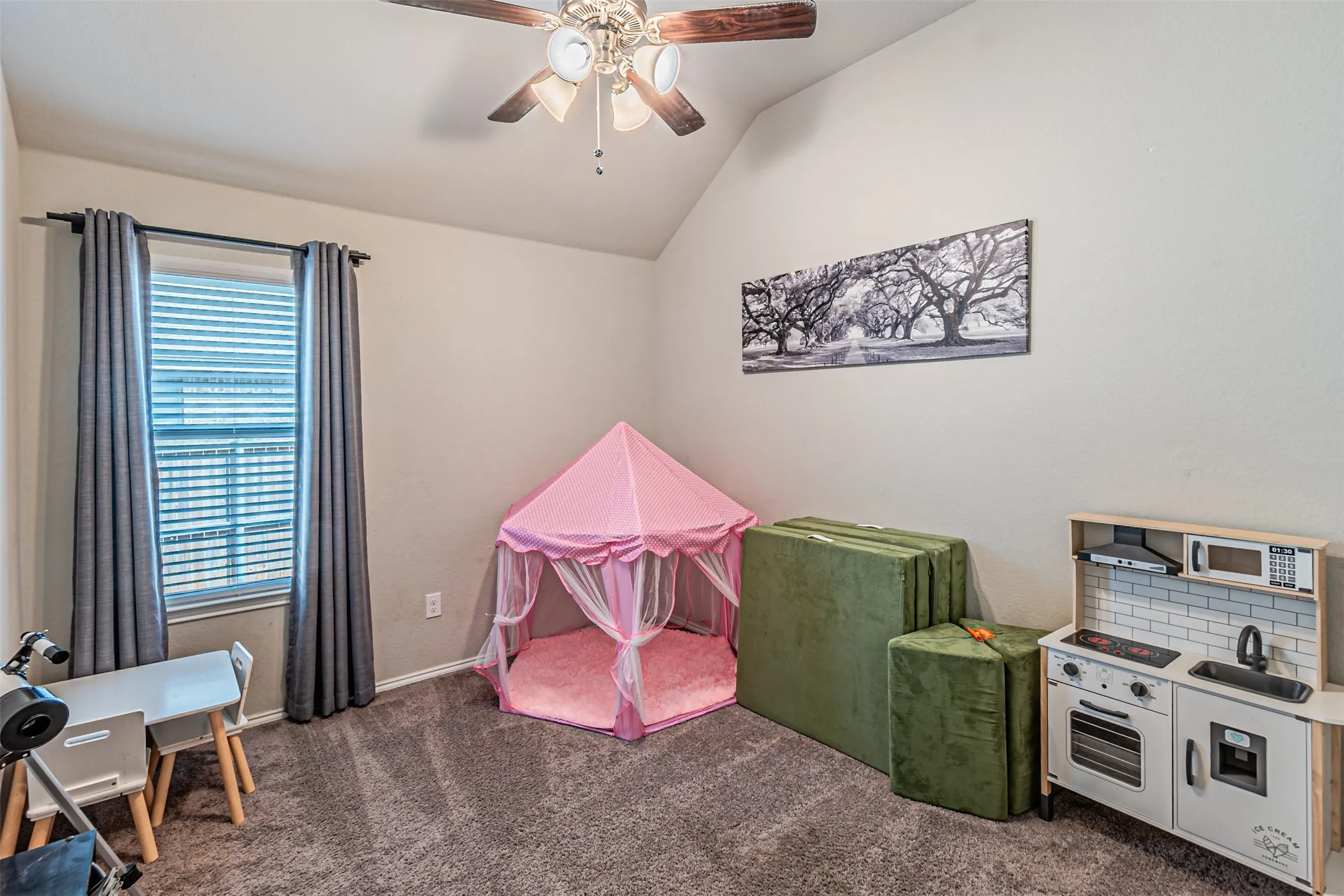 Playroom featuring ceiling fan, vaulted ceiling, and dark colored carpet