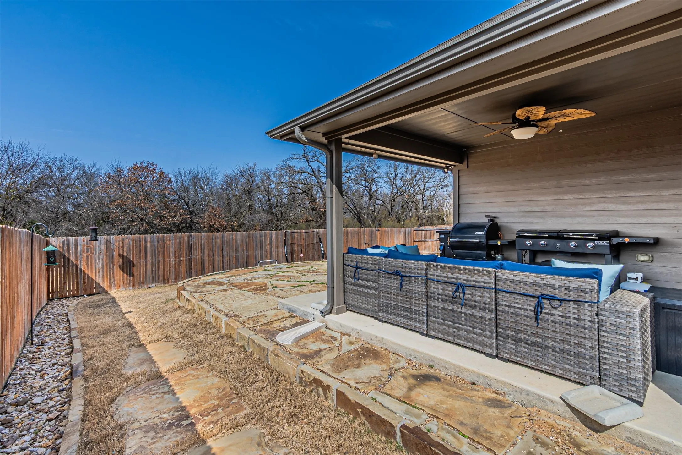 Fenced backyard featuring an outdoor hangout area, ceiling fan, a patio area, and grilling area