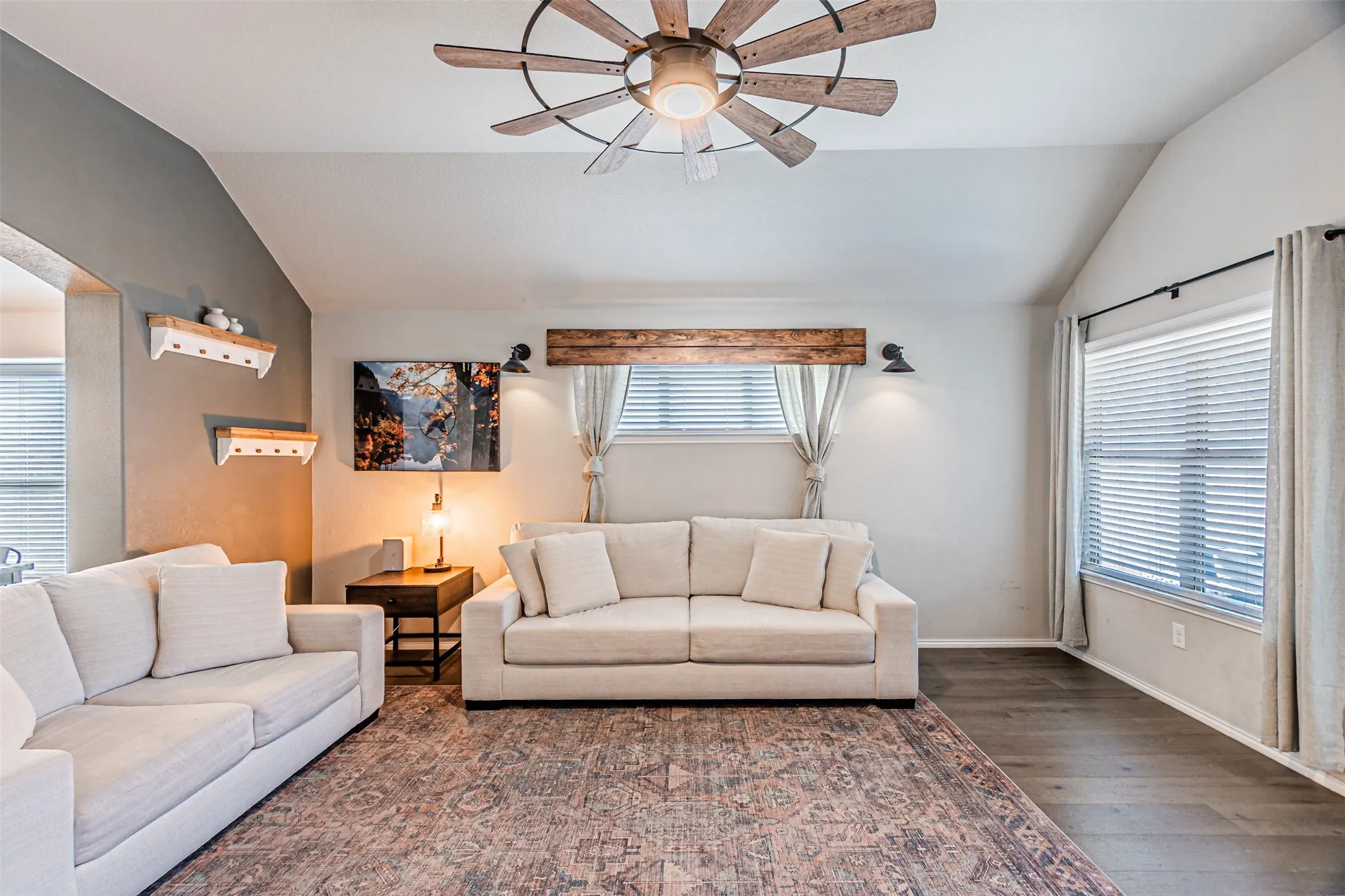 Living room with lofted ceiling, ceiling fan, and wood finished floors