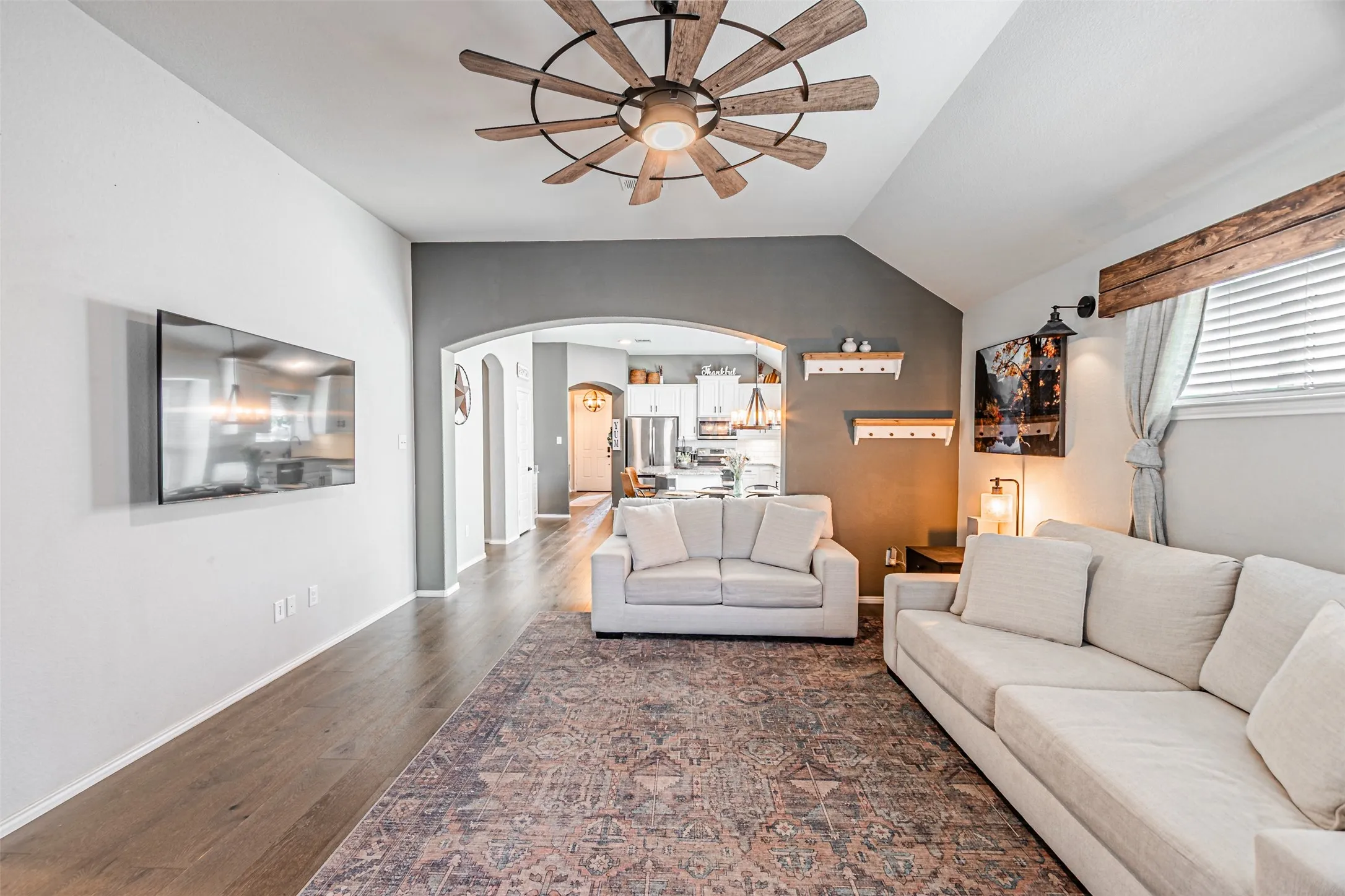 Living area featuring arched walkways, ceiling fan, dark wood-style flooring, and lofted ceiling