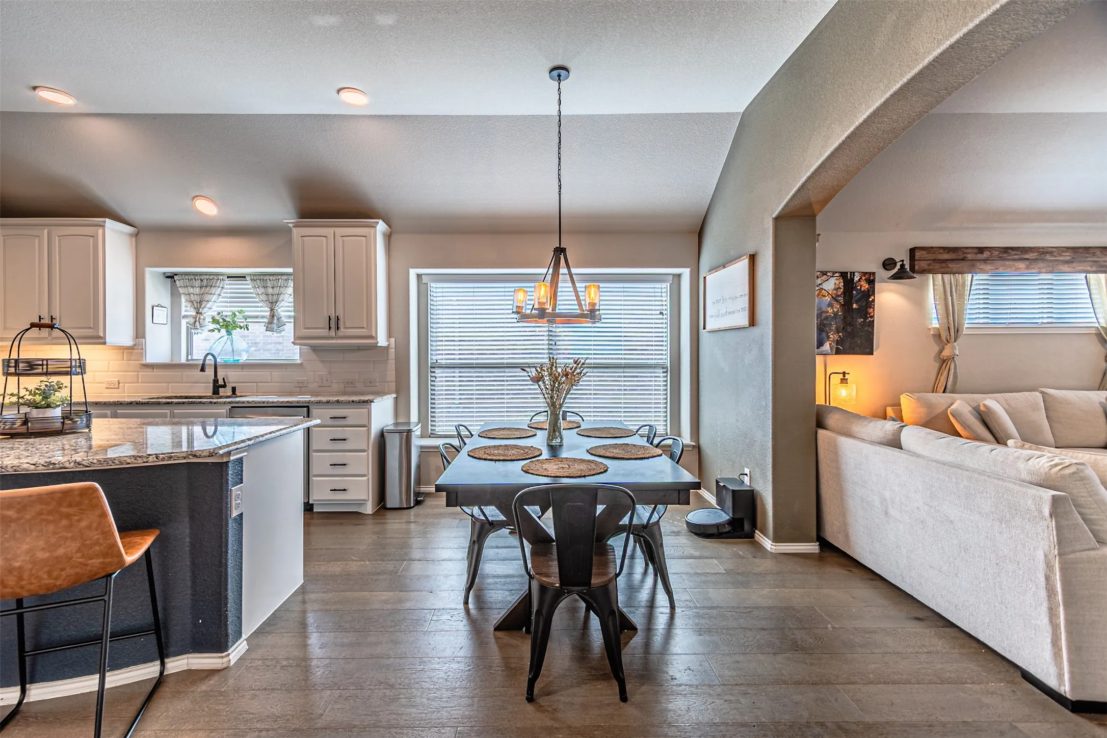 Kitchen featuring light stone countertops, open floor plan, decorative backsplash, and dark wood-style floors