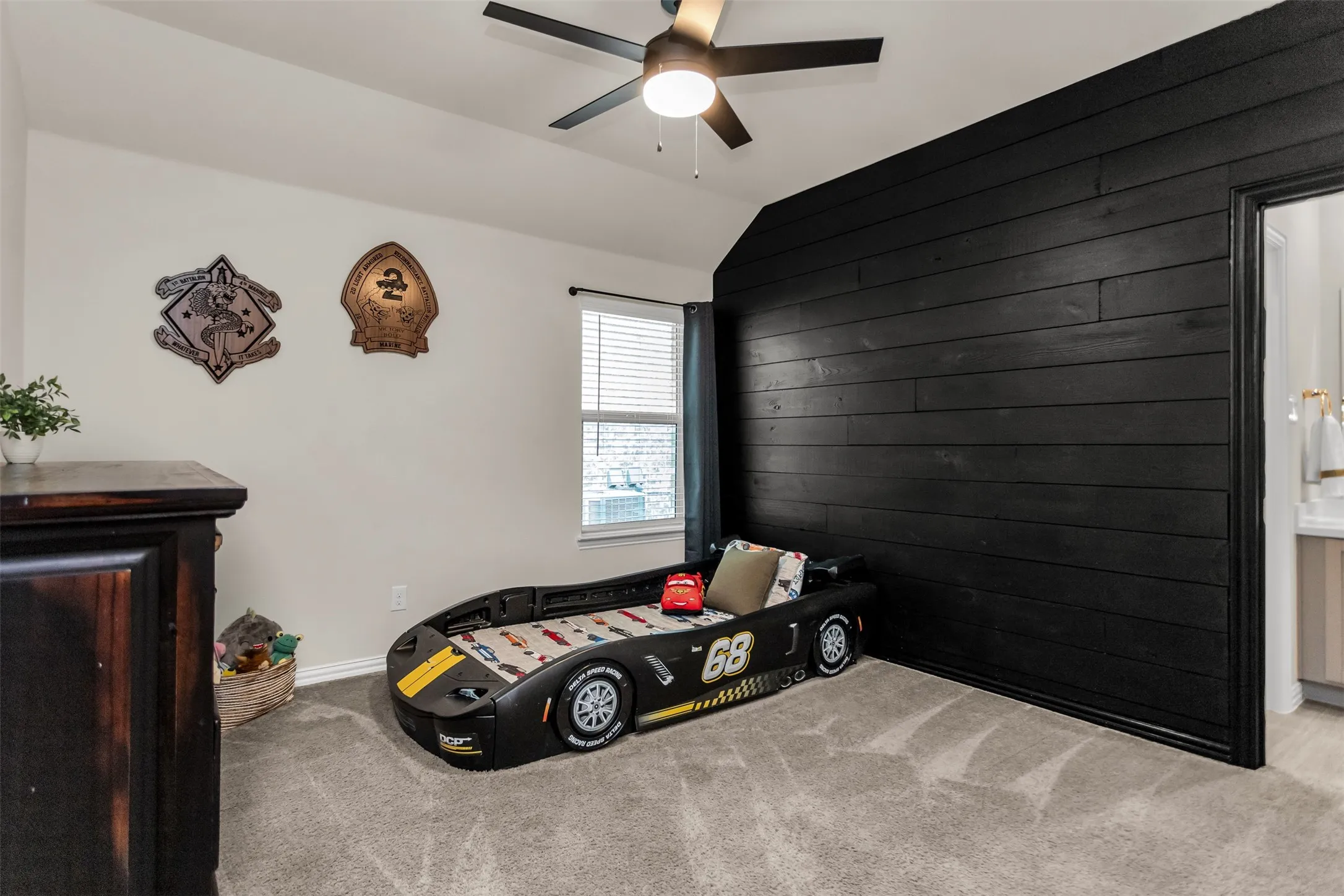 Bedroom featuring a vaulted ceiling, wood-finish accent wall, and a ceiling fan with integrated lighting