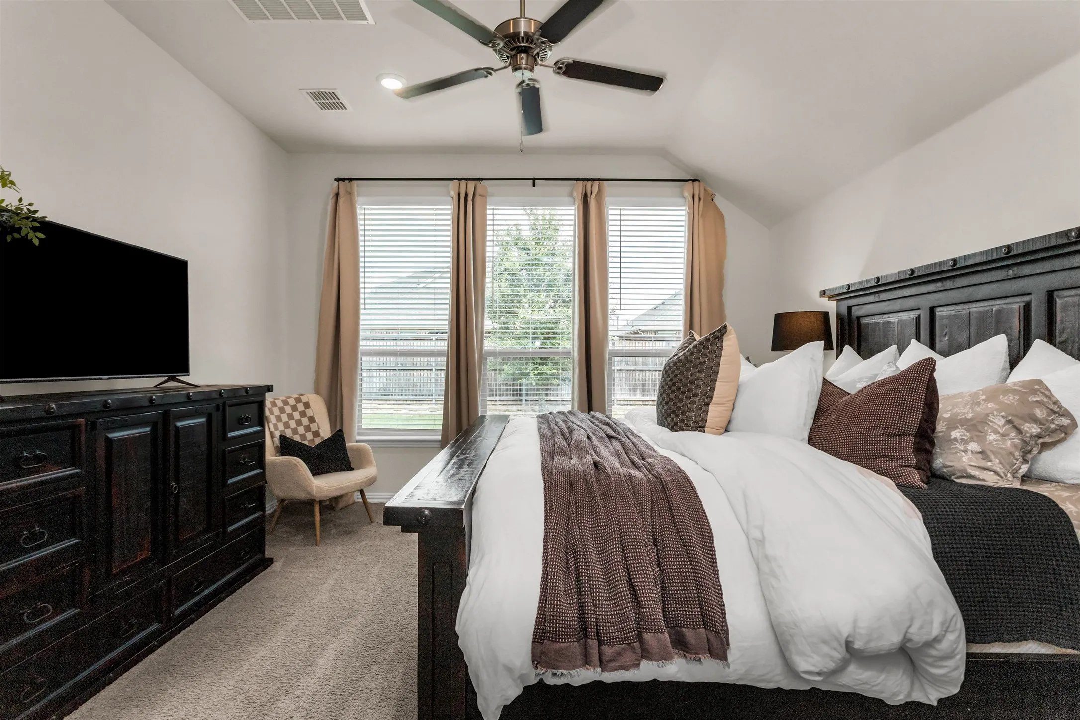 Vaulted ceiling with a ceiling fan and recessed lighting, three windows with blinds and curtains, and carpeted flooring