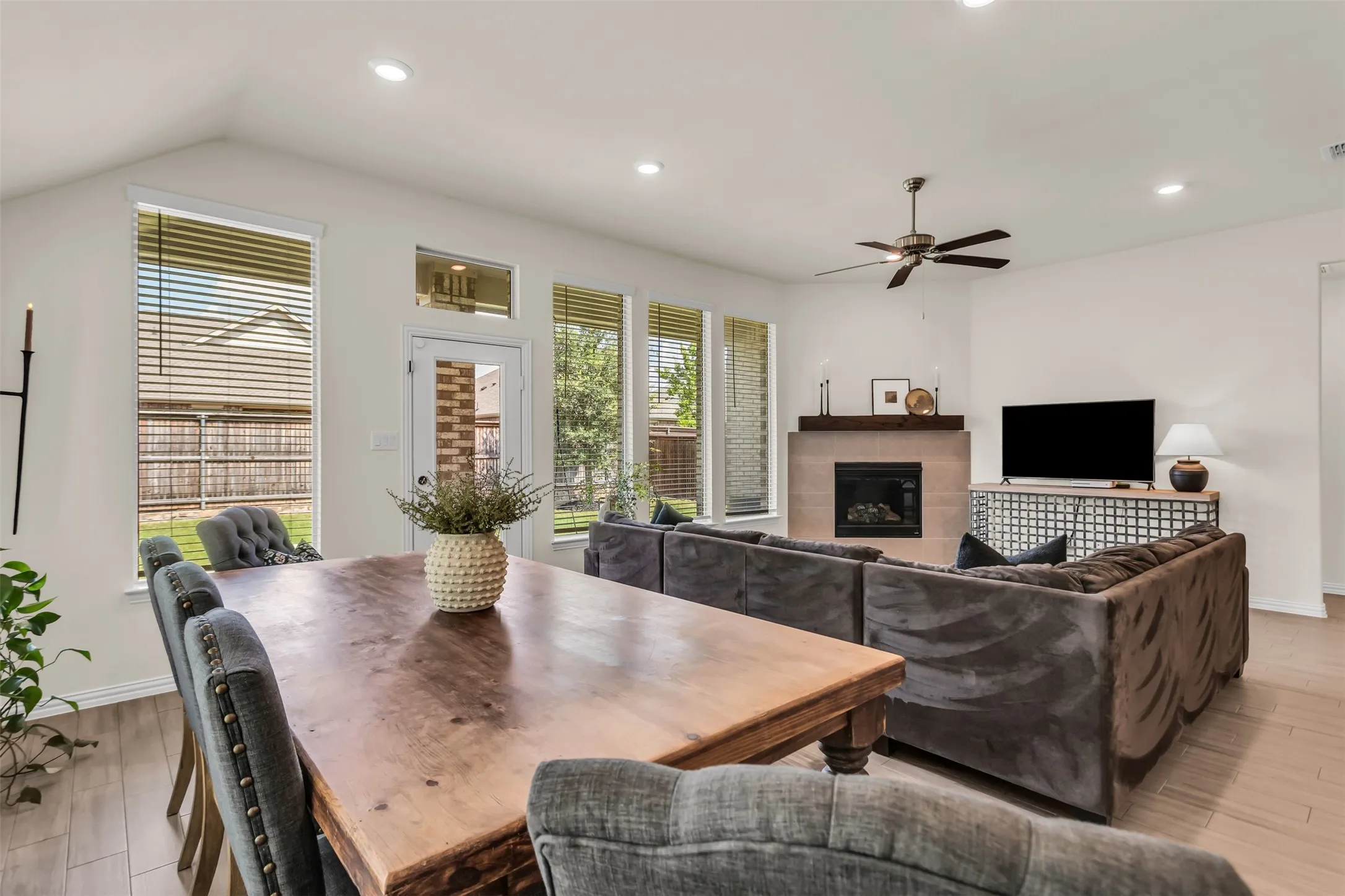 Vaulted ceiling with recessed lighting, wood-finish flooring, multiple windows, and a built-in fireplace with a mantel