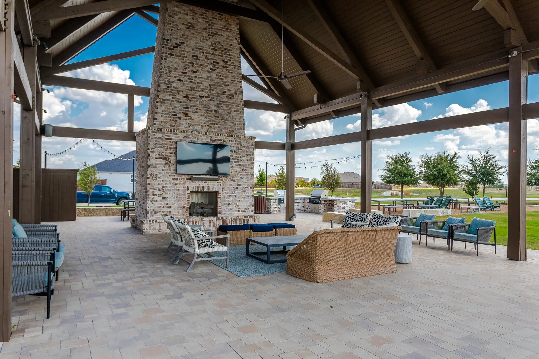Covered outdoor patio featuring an exposed beam ceiling, a brick fireplace, built-in outdoor grill, and paver flooring